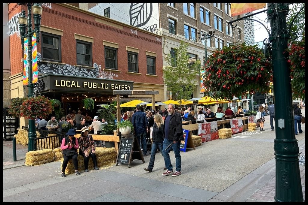 An image showing people sitting on outdoor patios and walking down Stephen Ave in downtown Calgary.