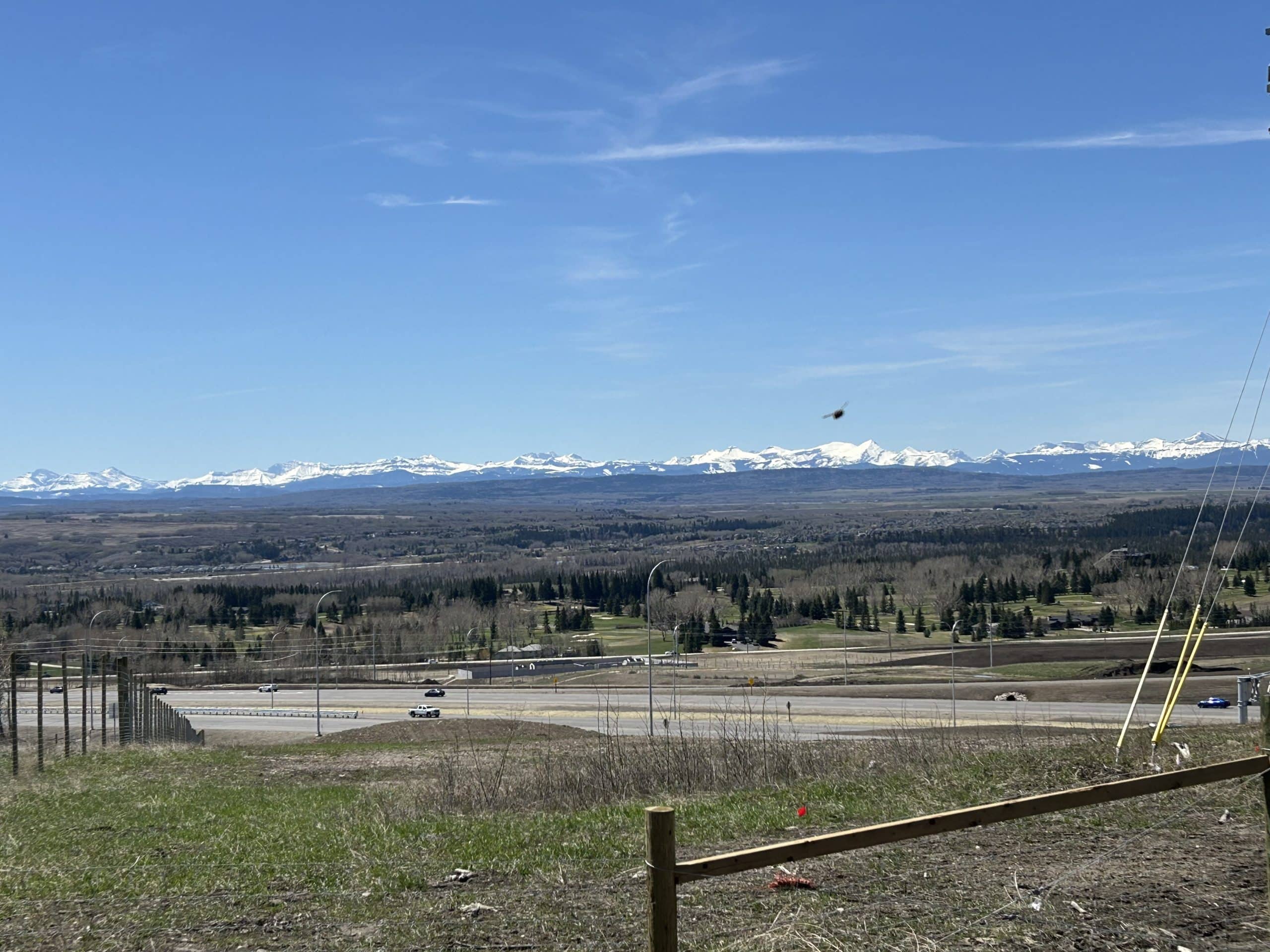 A sunny day view of the Stoney Trail ring road in West Springs showing smooth traffic flow and scenic surroundings.