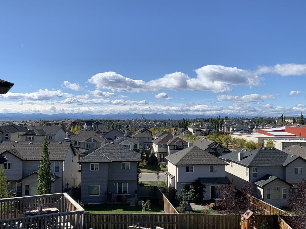 Elevated view of Royal Oak Calgary with rows of single family detached houses and views of the Rocky Mountains in the distance.