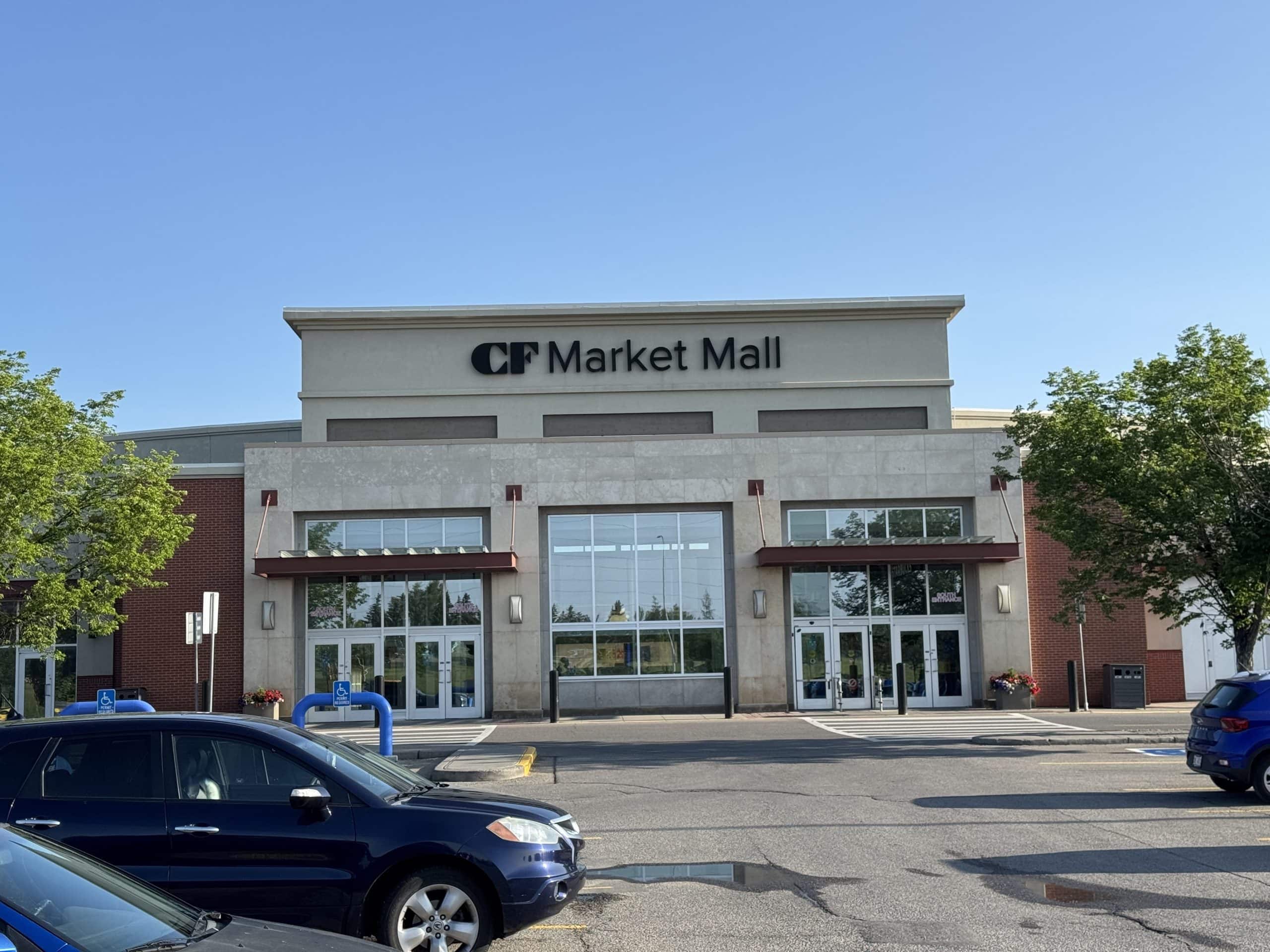 Entrance to CF Market Mall near Montgomery Calgary with parked cars and sunny skies.