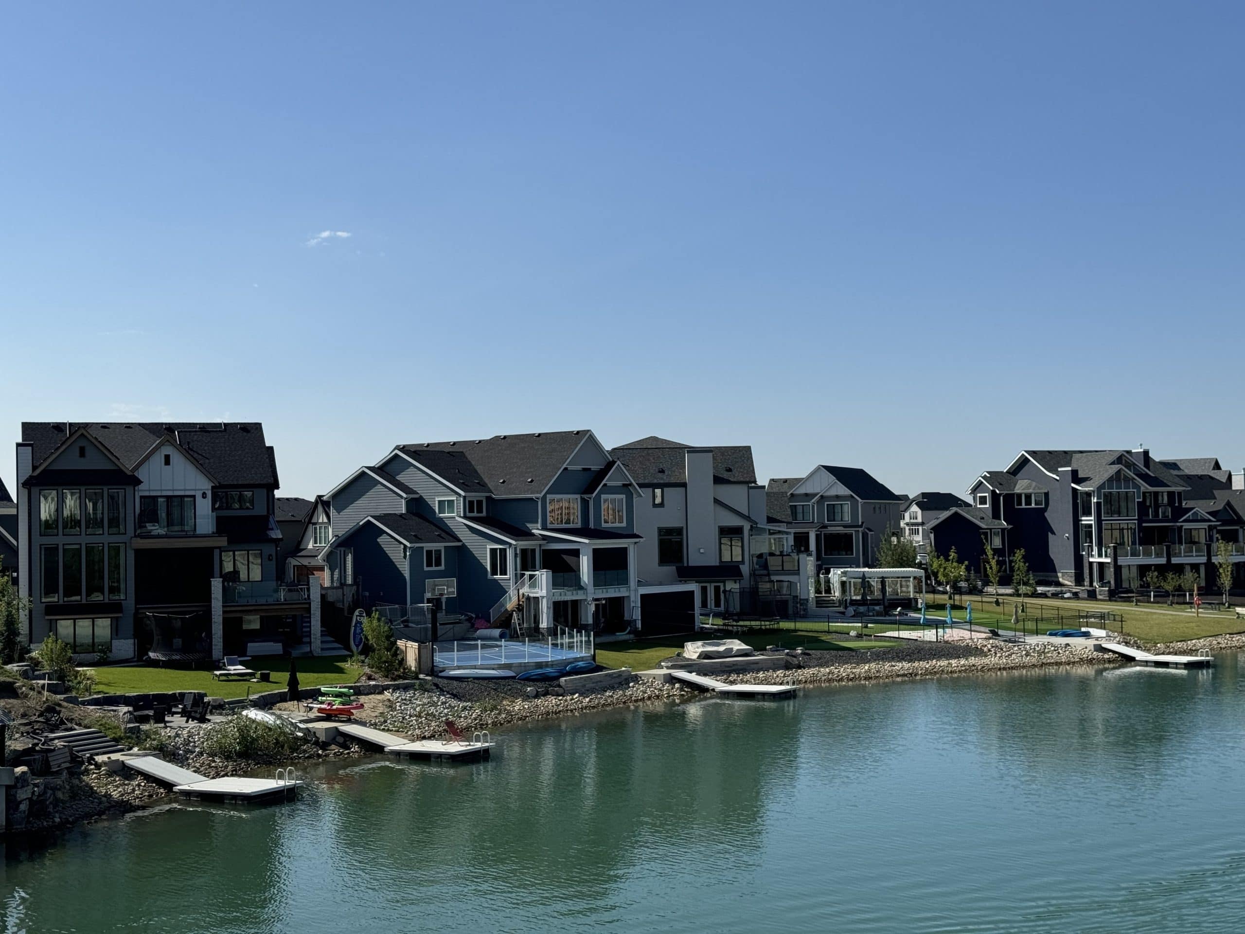 Scenic view of a Calgary lake community with waterfront homes and a walking path