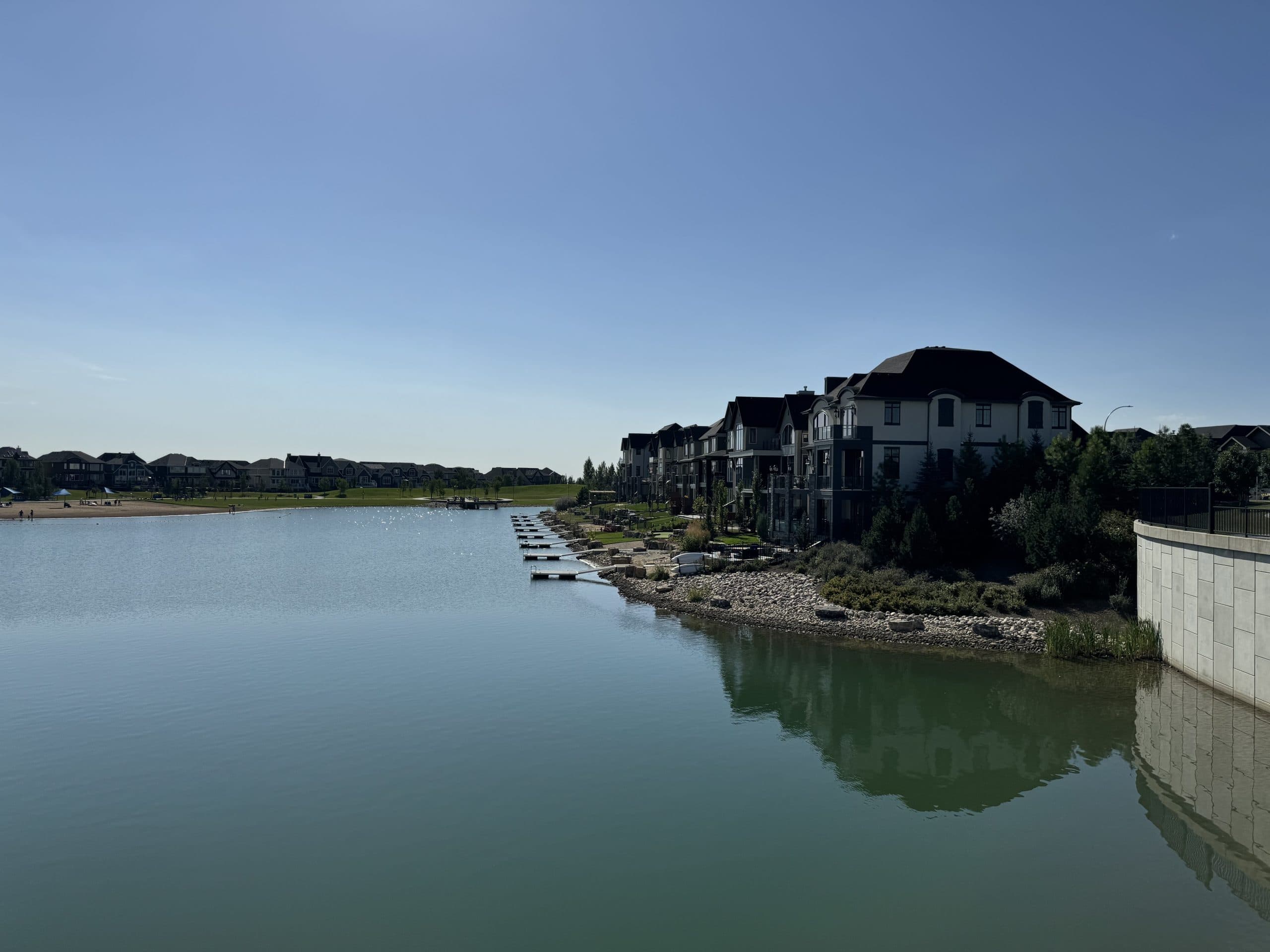 Mahogany Lake waterfront homes in Calgary with private docks and peaceful water views on a sunny day.