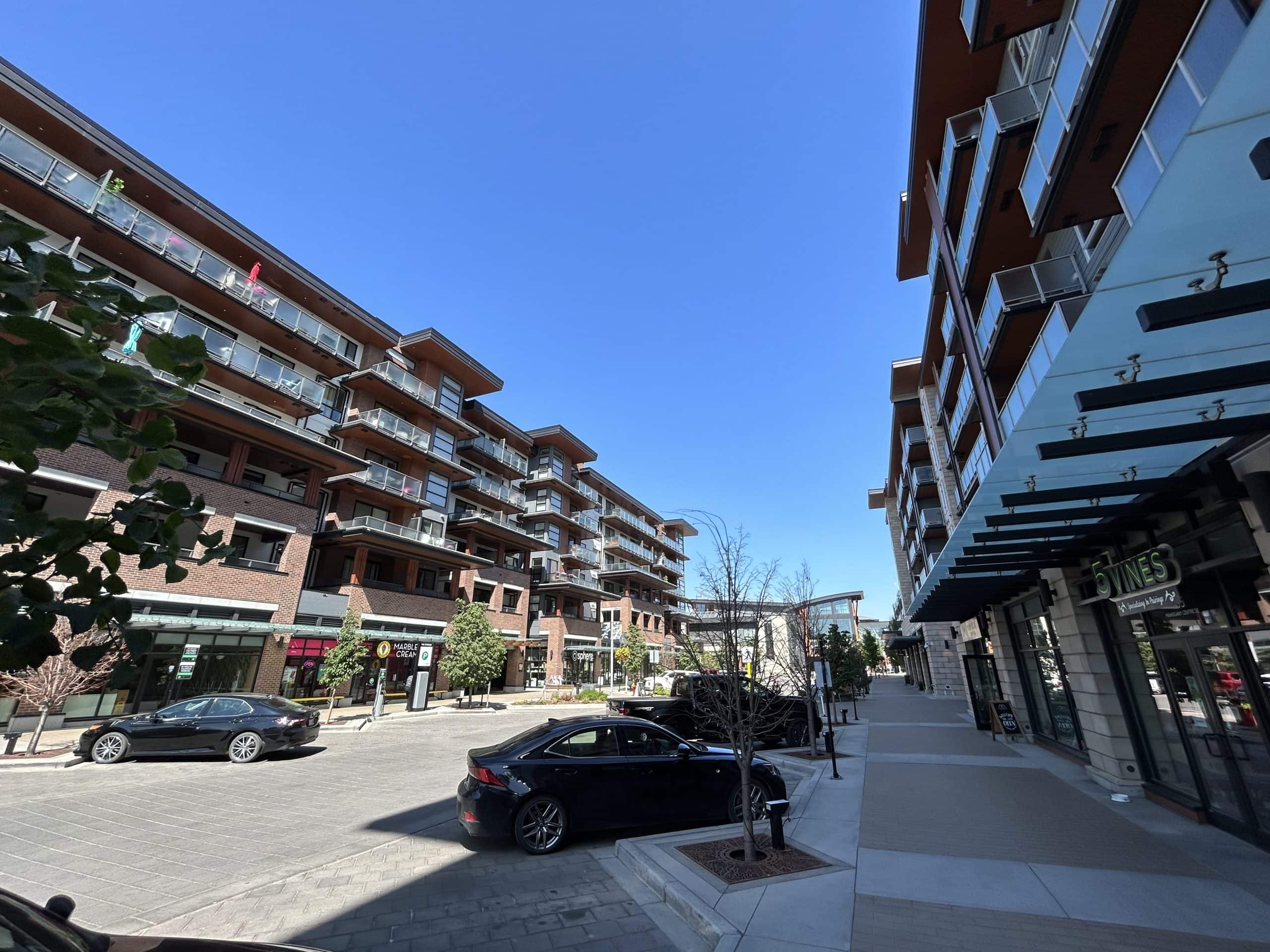 Modern condo buildings and retail shops at Westman Village in Mahogany Calgary, featuring a walkable street with restaurants, cafes, and boutique services.