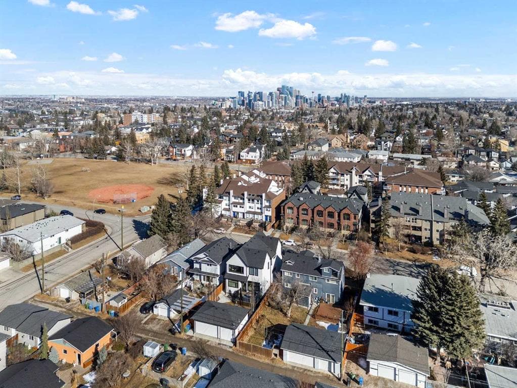 Aerial view of Killarney Calgary highlighting residential streets, nearby parks, and a clear view of the downtown skyline, showcasing urban convenience and charm.