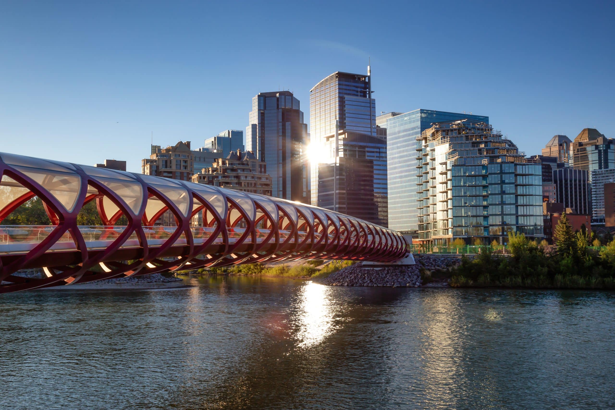 Peace Bridge across Bow River during a vibrant summer sunrise. Taken in Calgary, Alberta, Canada.