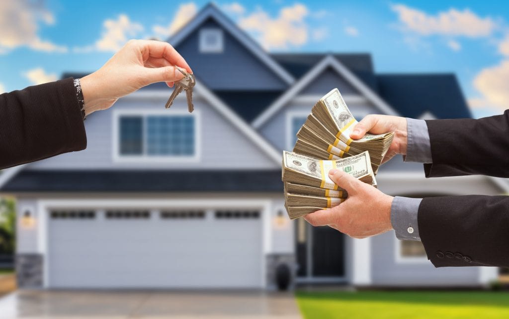 Real Estate Agent Handing Over House Keys for Stacks of Money in Front of New House.