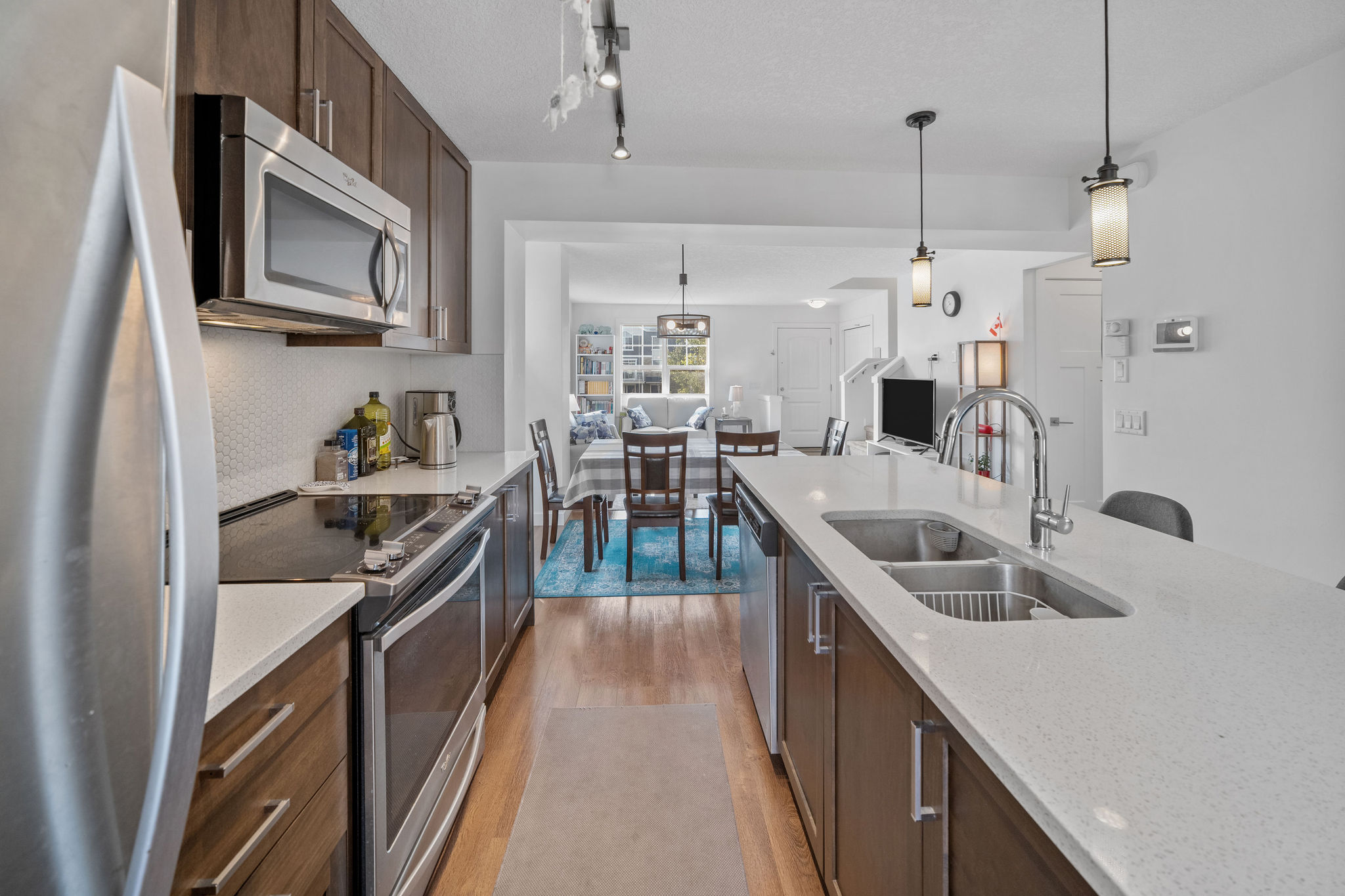 Stylish kitchen with quartz countertops, stainless steel appliances, and a functional island with double sinks. Open design connects seamlessly to the dining and living areas, perfect for everyday living and entertaining.