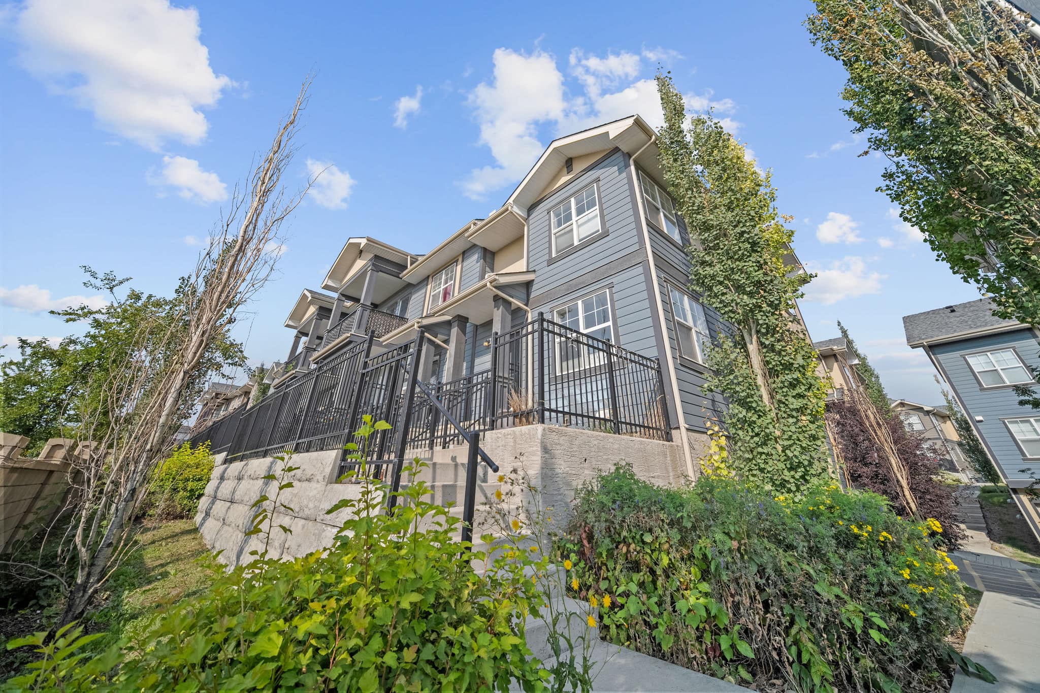 Beautiful corner townhome with a modern exterior, private fenced patio, and landscaped surroundings. Elevated design provides curb appeal and a welcoming presence in a desirable community setting.