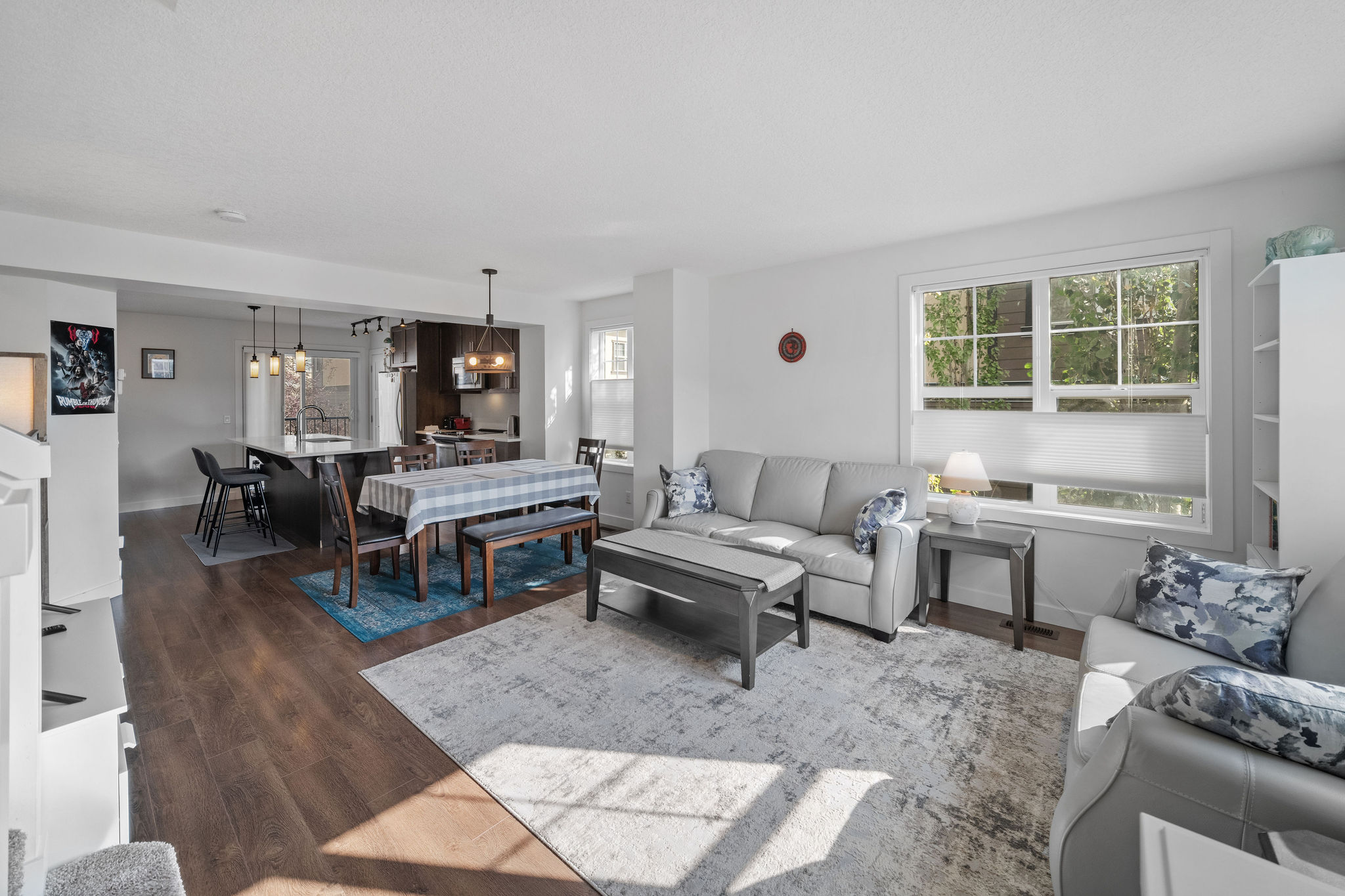 Bright open-concept living space with large windows, modern flooring, and a seamless flow from the living room to the dining area and kitchen. Stylish finishes and natural light create a welcoming atmosphere perfect for both relaxing and entertaining.