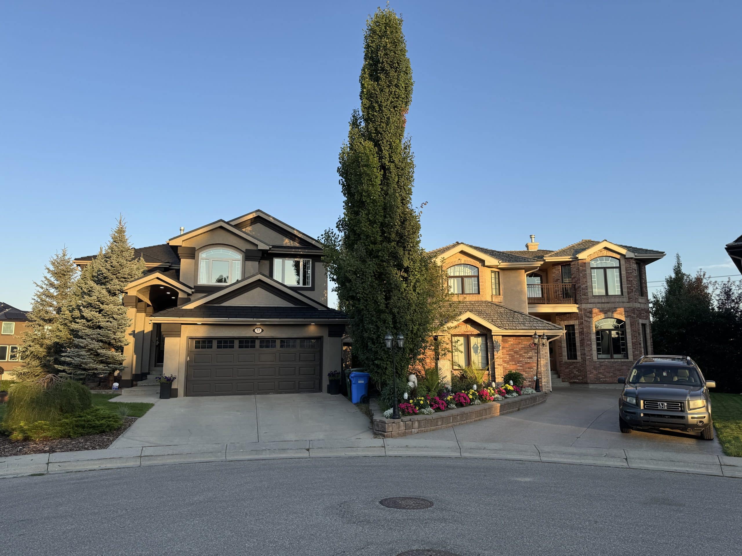 Beautiful two storey homes in Evergreen Estates Calgary captured in the warm evening light, showcasing elegant architecture, manicured yards, and a quiet residential street.