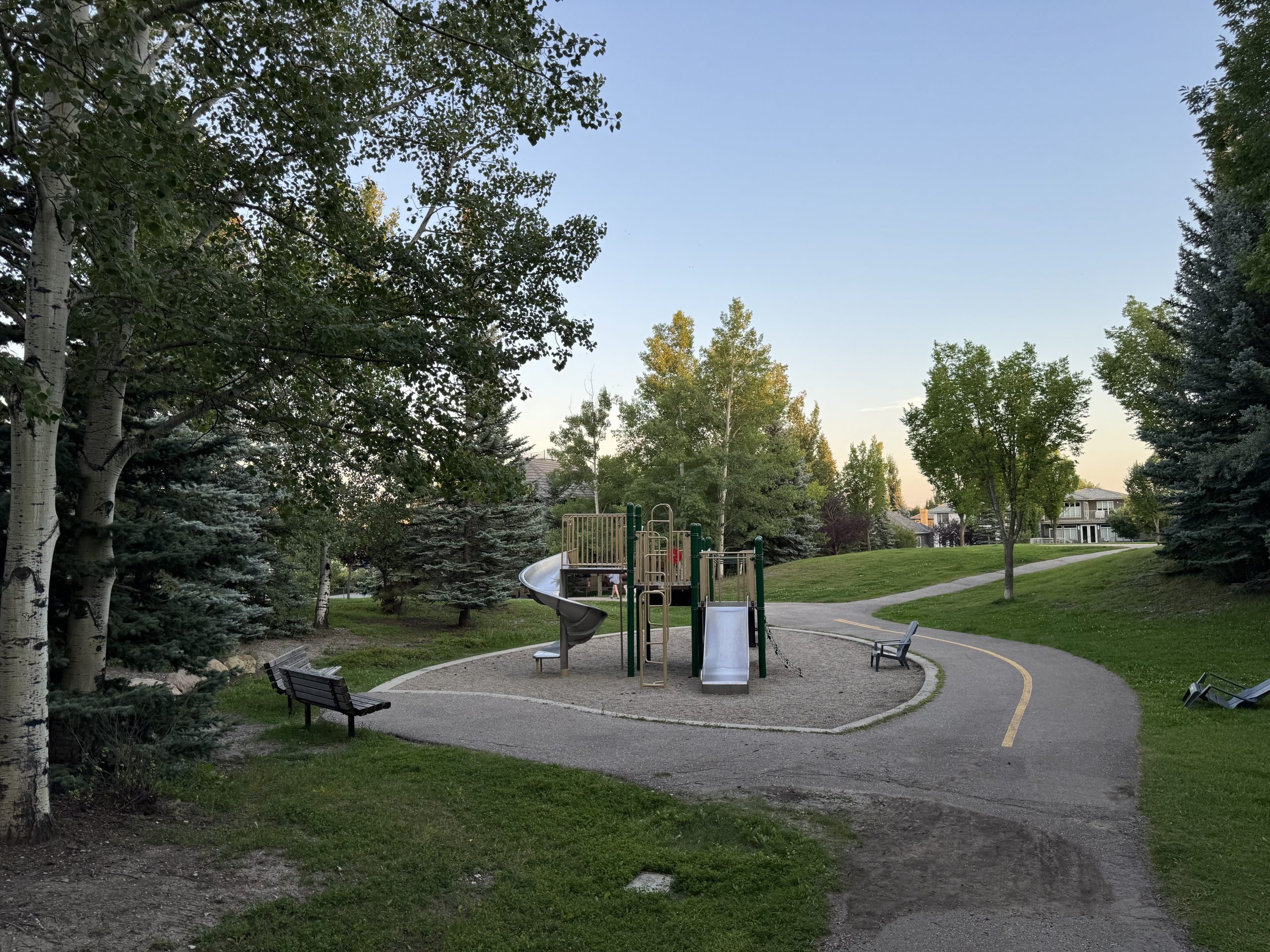 Quiet residential park in Evergreen Calgary featuring a children’s playground, walking paths, and mature trees, reflecting the family-friendly atmosphere of this southwest neighbourhood.