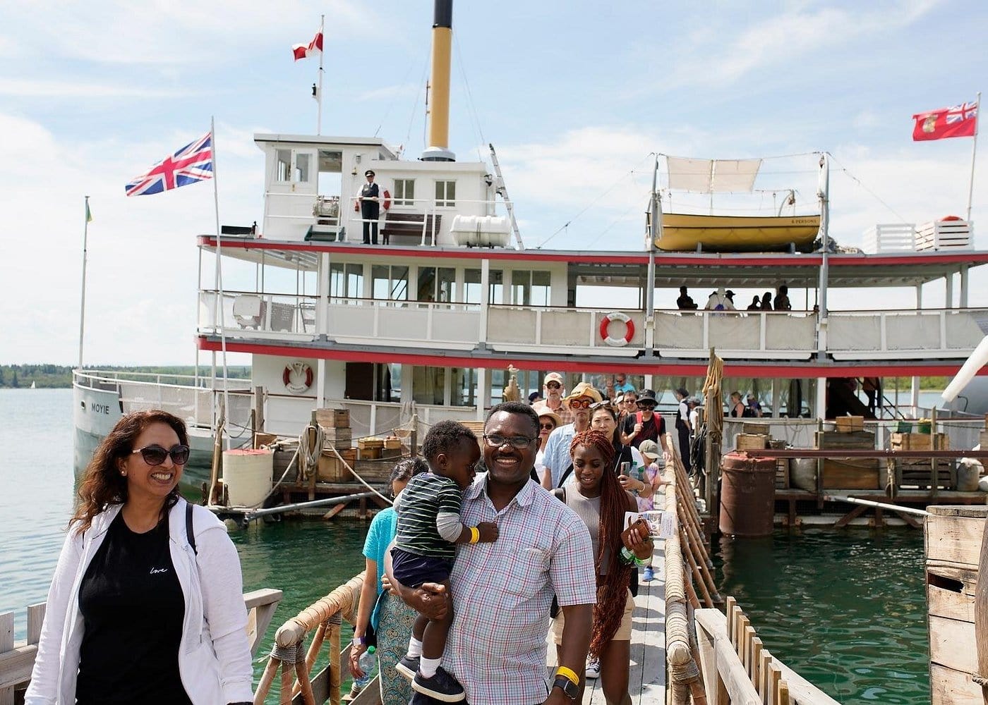 Visitors disembarking from the historic S.S. Moyie paddlewheeler at Heritage Park in Calgary, enjoying a sunny day on Glenmore Reservoir with scenic views and vintage maritime charm.