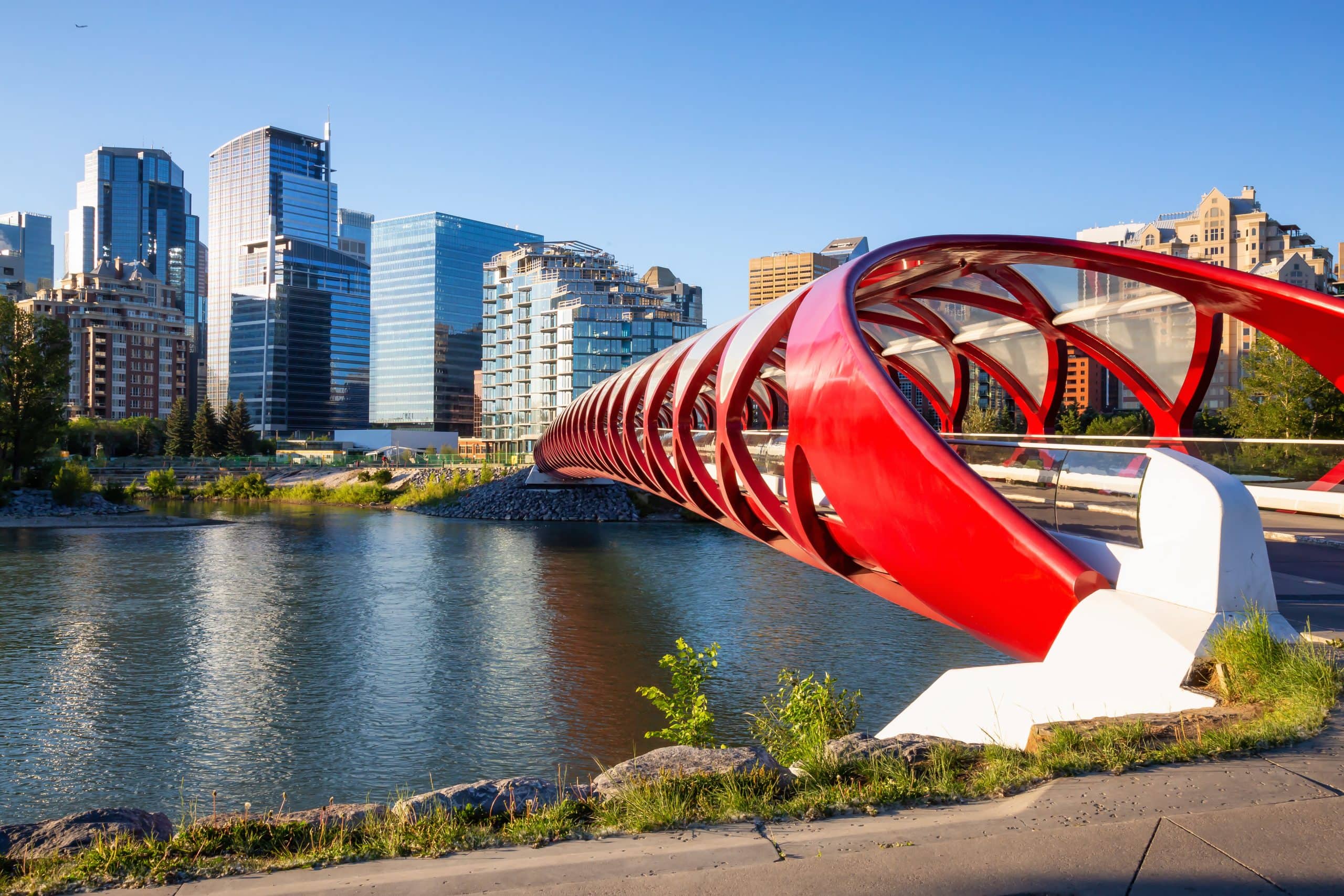 Peace Bridge across Bow River during a vibrant summer sunrise. Taken in Calgary, Alberta, Canada.