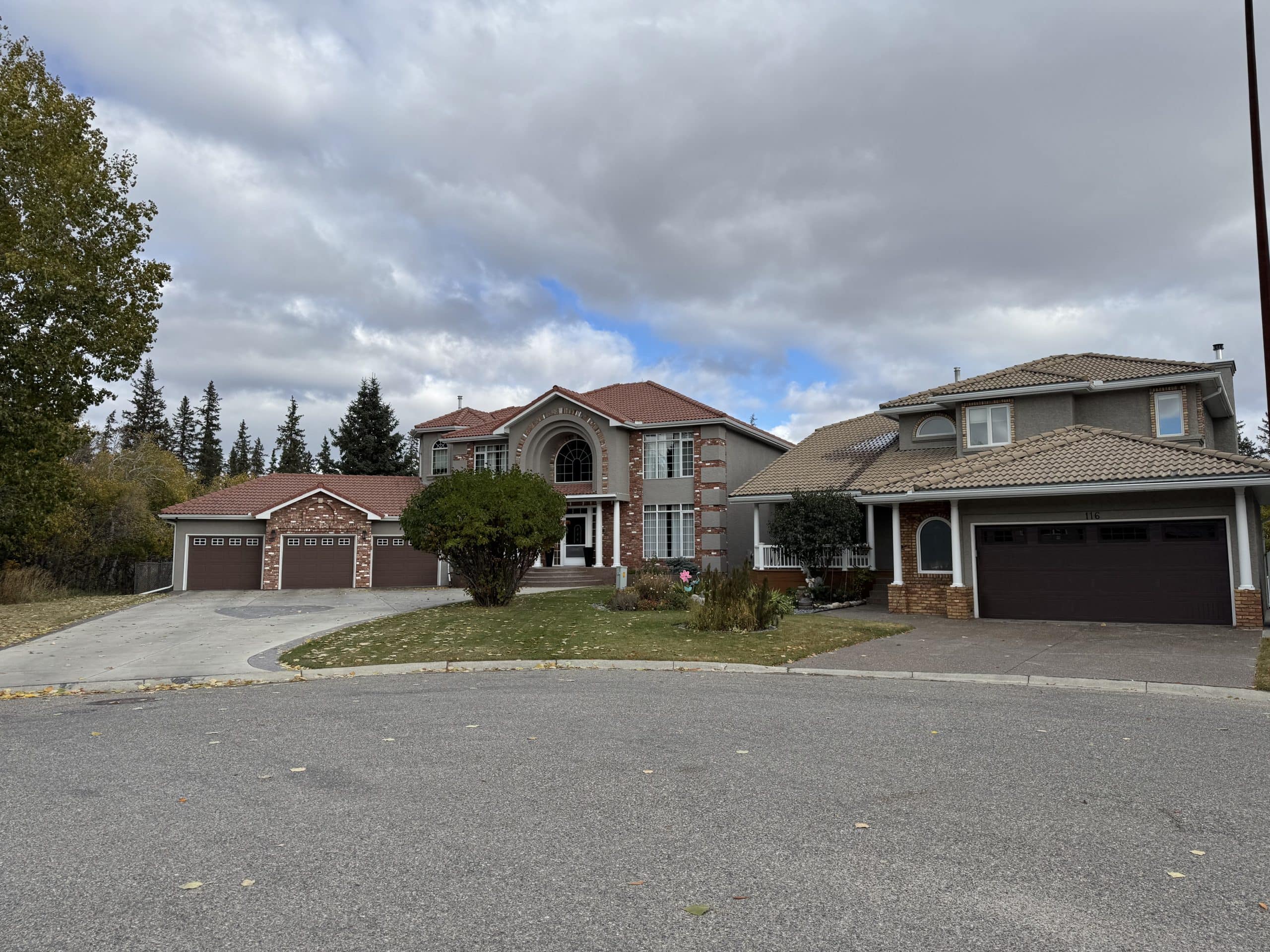 Large estate style homes in Shawnee Slopes Calgary with tile roofs and mature trees on a quiet cul de sac, highlighting the neighbourhood’s upscale residential feel.