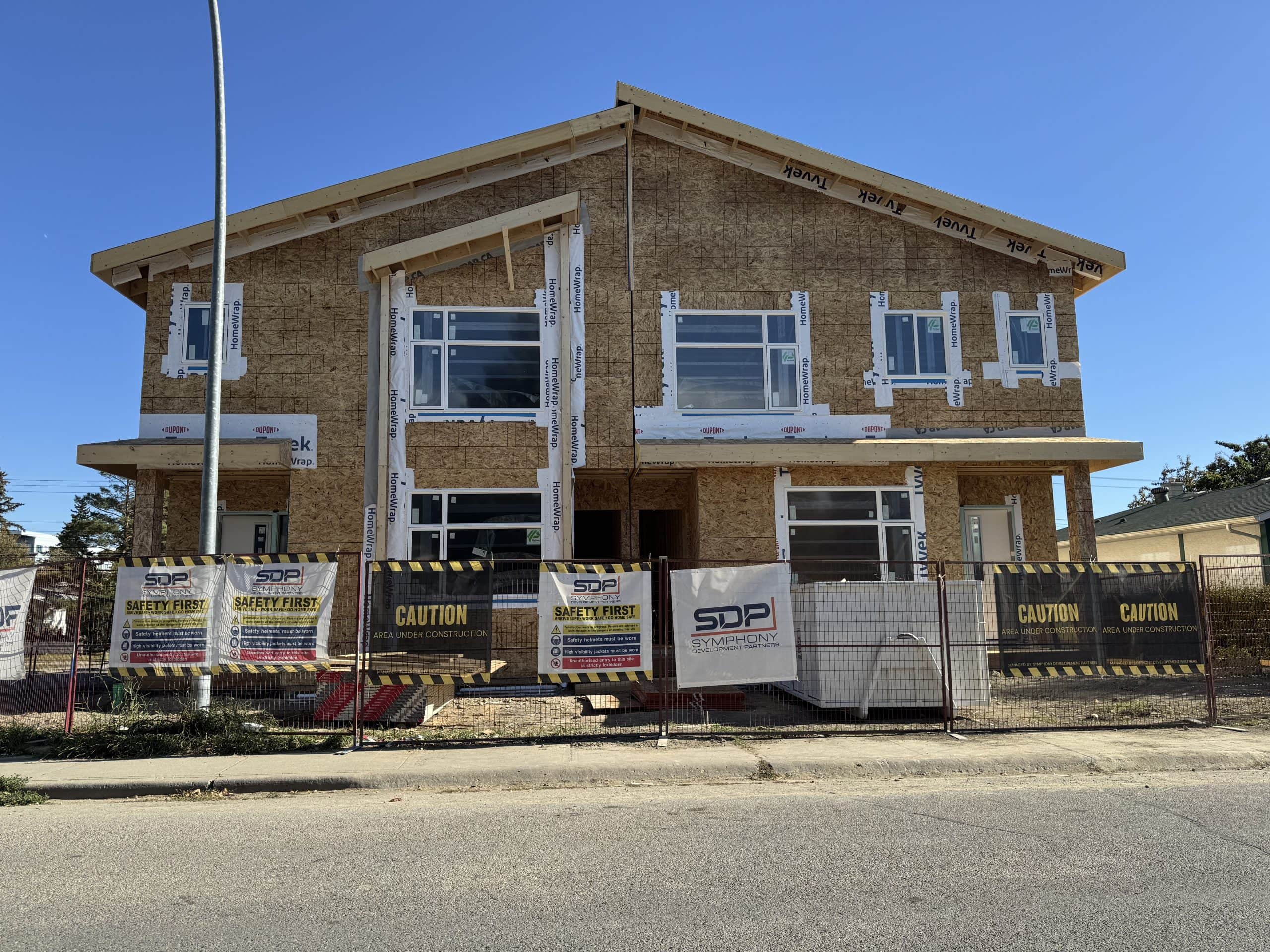 New home construction in Kingsland showing a modern duplex build with safety fencing and a clear blue sky in the background.