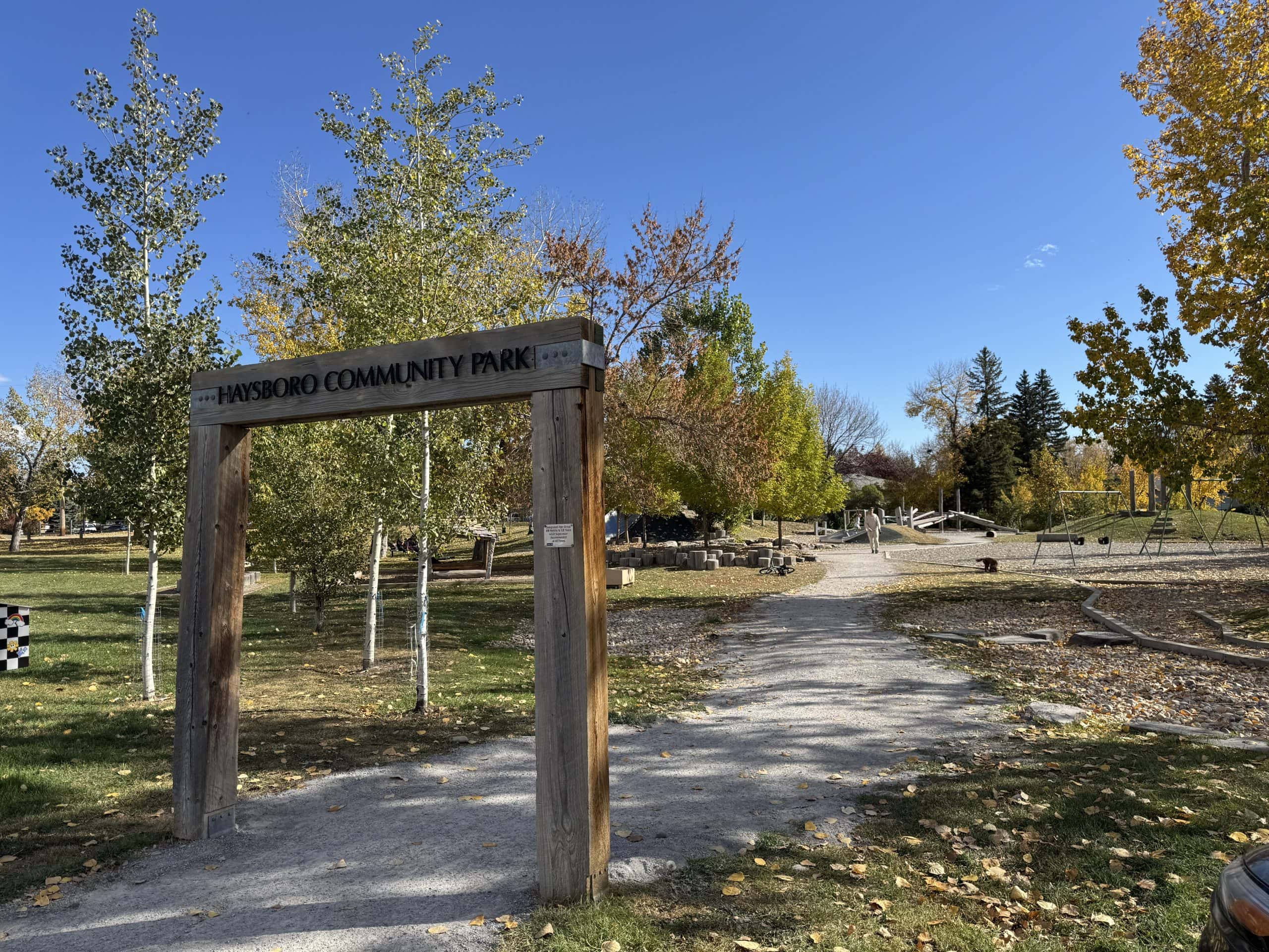 Haysboro Community Park with fall trees, a natural playground, open green space, and a clear blue sky.