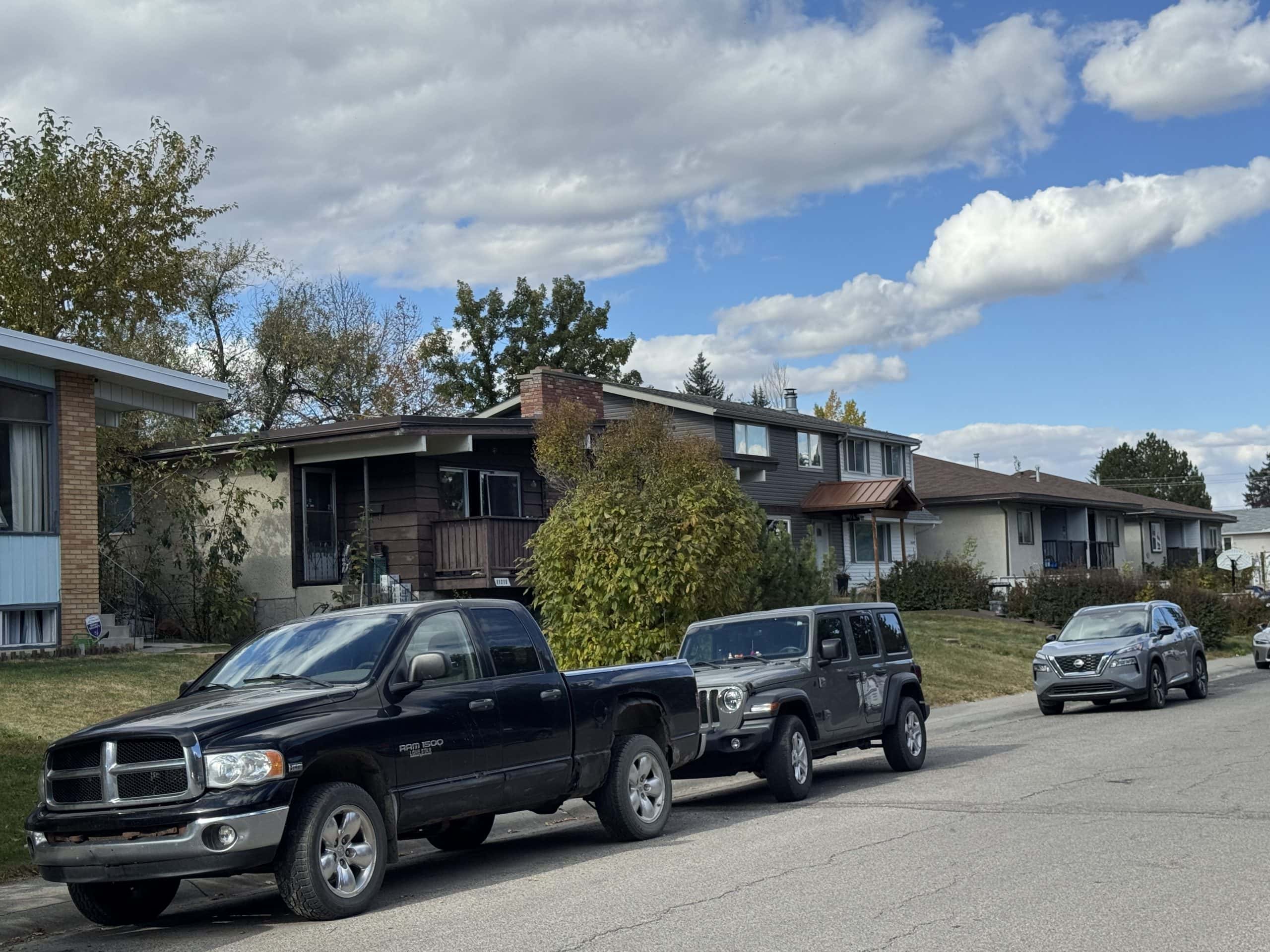 Residential street in Southwood with older single family homes, parked vehicles, mature trees, and a mix of sun and clouds in the sky.