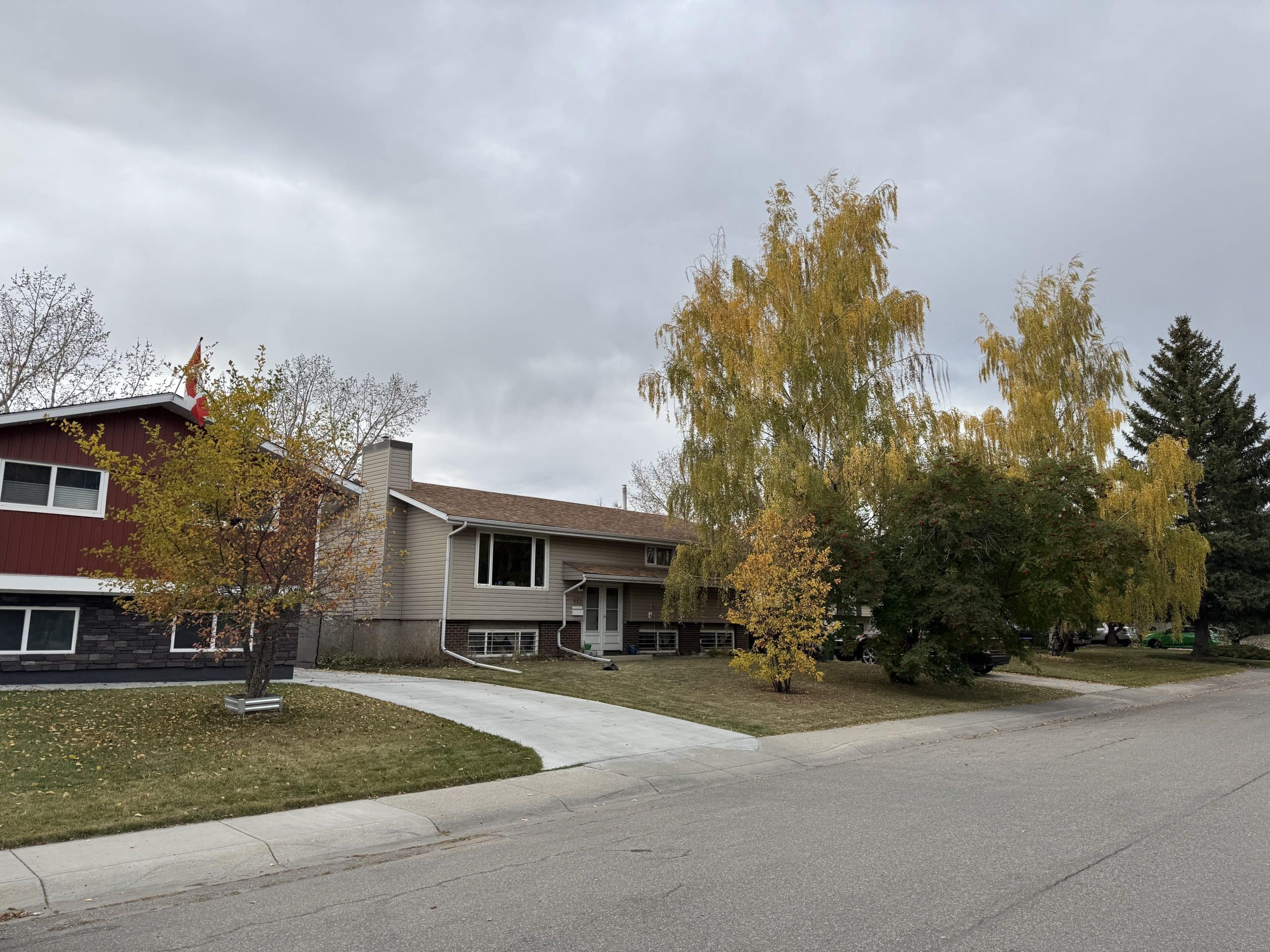 Quiet suburban street in Cedarbrae with mature trees, fall colours, and well kept split level homes under an overcast sky.