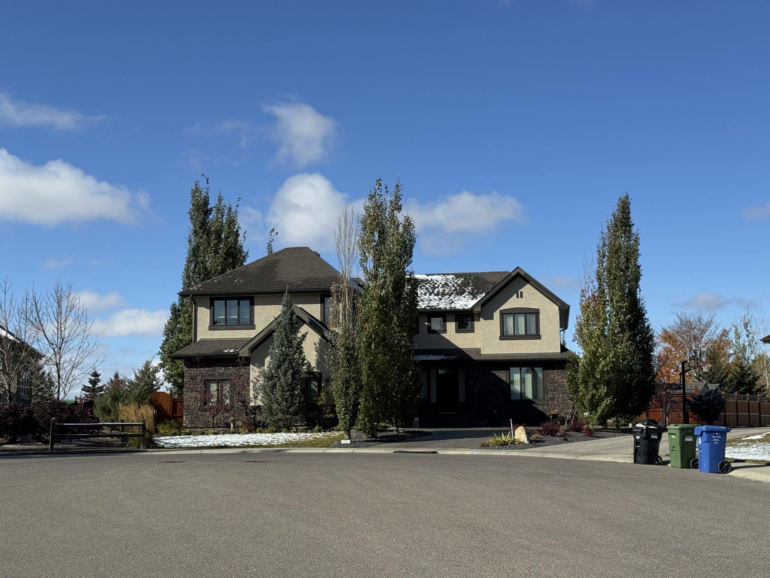Quiet street in Silverado with a large modern two storey home, tall trees, and early winter light that highlights the calm upscale feel of this southern Calgary neighbourhood.