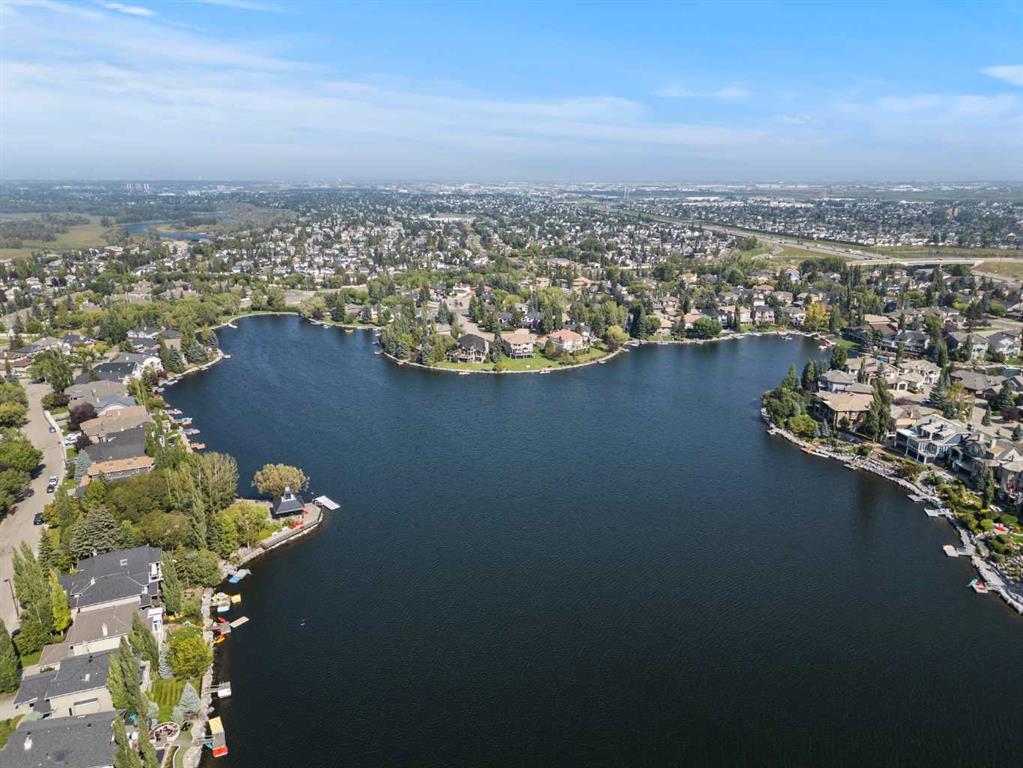 Aerial view of luxury waterfront homes surrounding McKenzie Lake, highlighting private lake access, mature landscaping, larger estate properties, and one of Calgary's most exclusive family oriented communities.