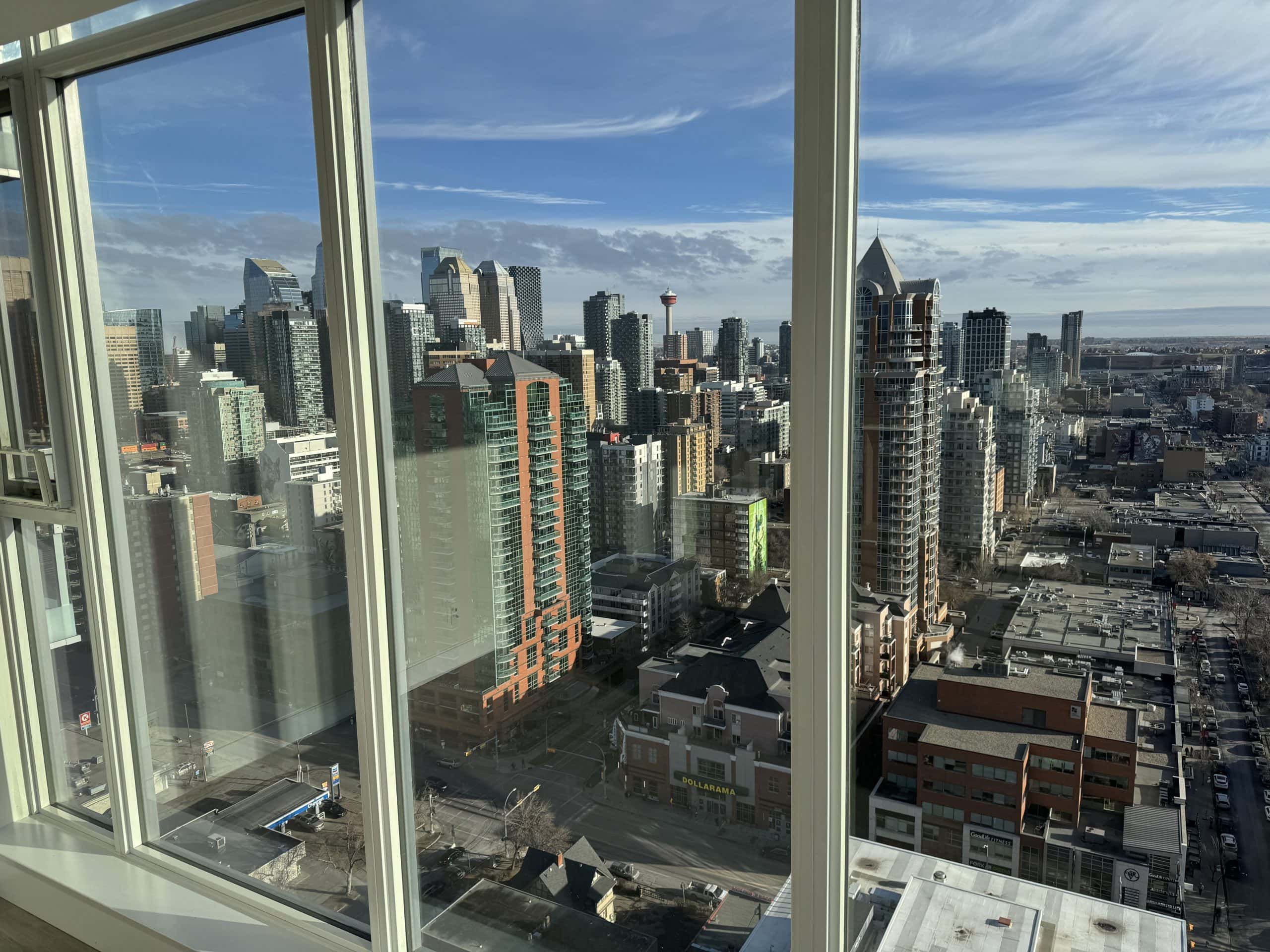 Panoramic downtown Calgary skyline views from a high rise condo featuring floor to ceiling windows and views of the Calgary Tower and Beltline.