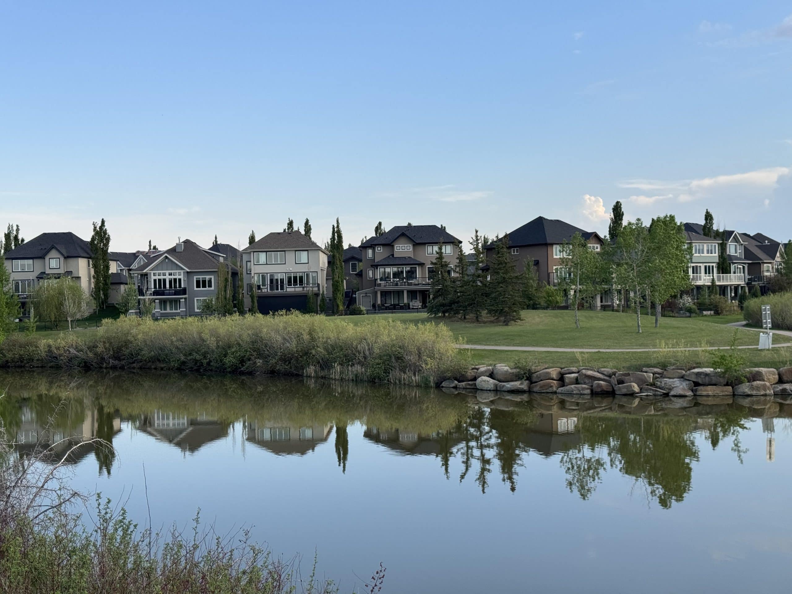 Luxury homes backing onto one of McKenzie Towne's scenic ponds, showcasing larger estate style properties, walking paths, green space, and the family friendly atmosphere that makes areas like Elgin and Inverness highly desirable.