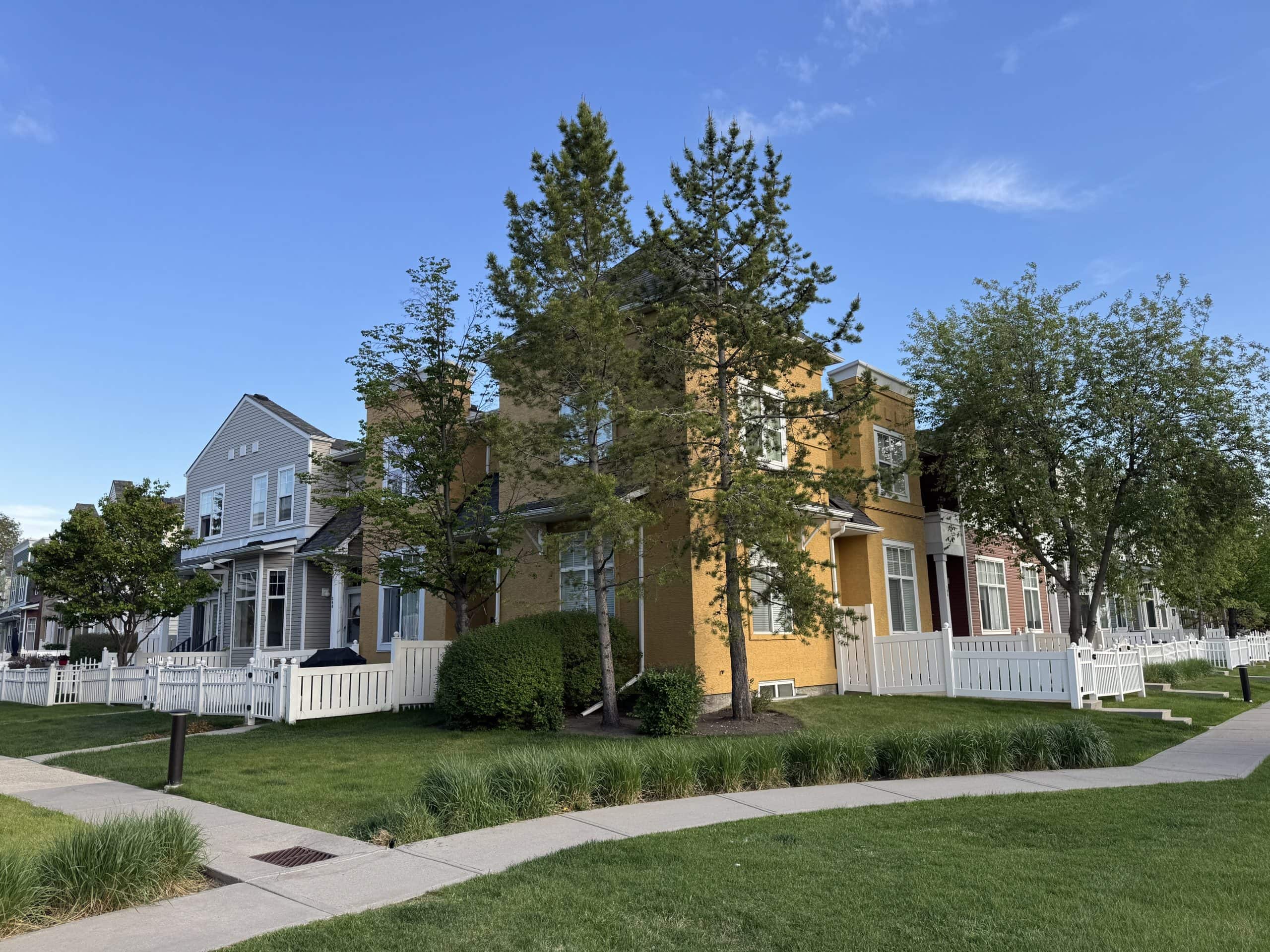 Townhomes in McKenzie Towne featuring landscaped streets, mature trees, front porches, and walkable access to parks, pathways, shopping, and community amenities in southeast Calgary.