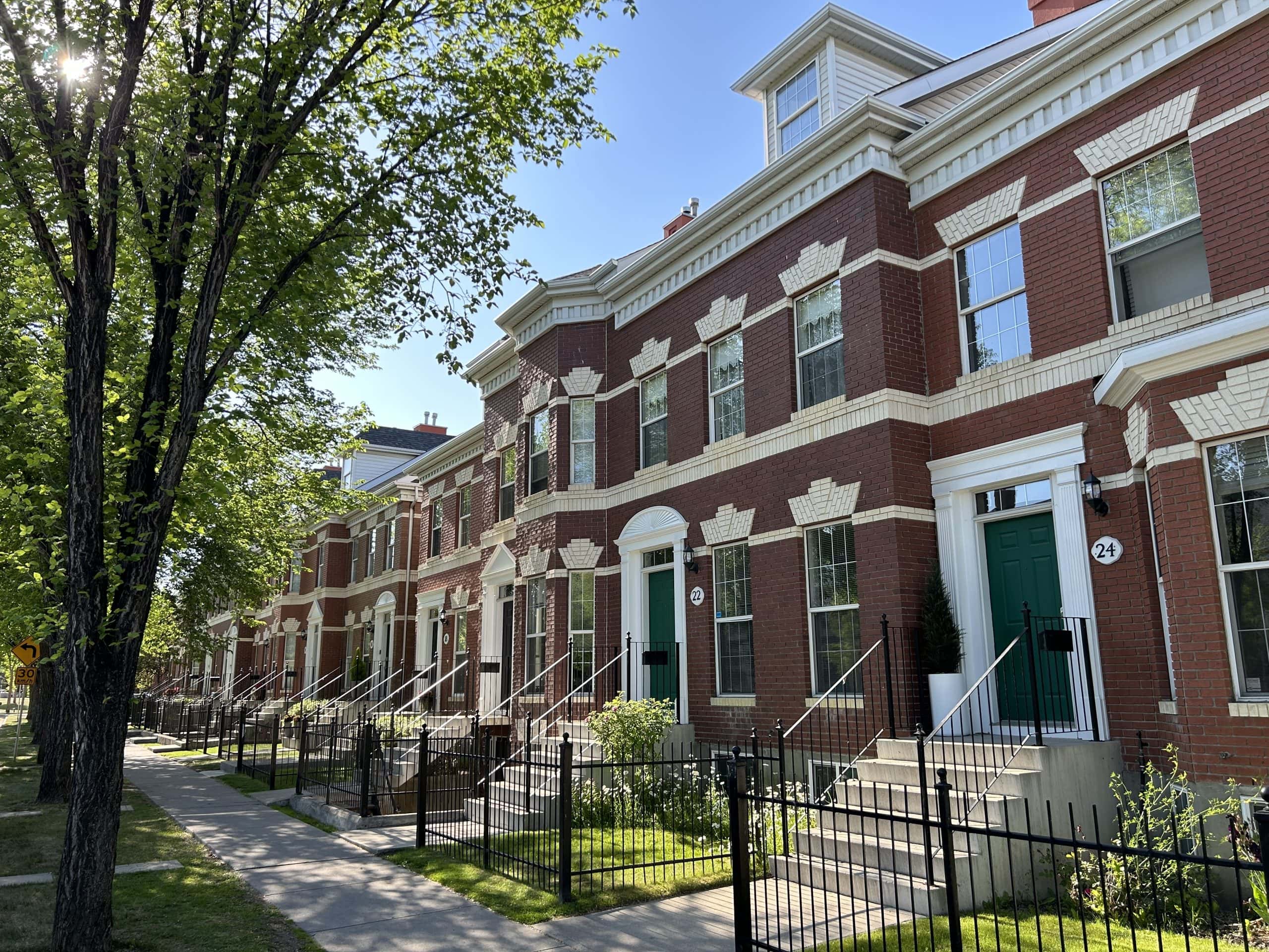 brick townhomes in the Inverness area of McKenzie Towne, showcasing the community’s distinctive architecture, tree lined streets, front porches, and walkable neighbourhood design inspired by traditional small town living.