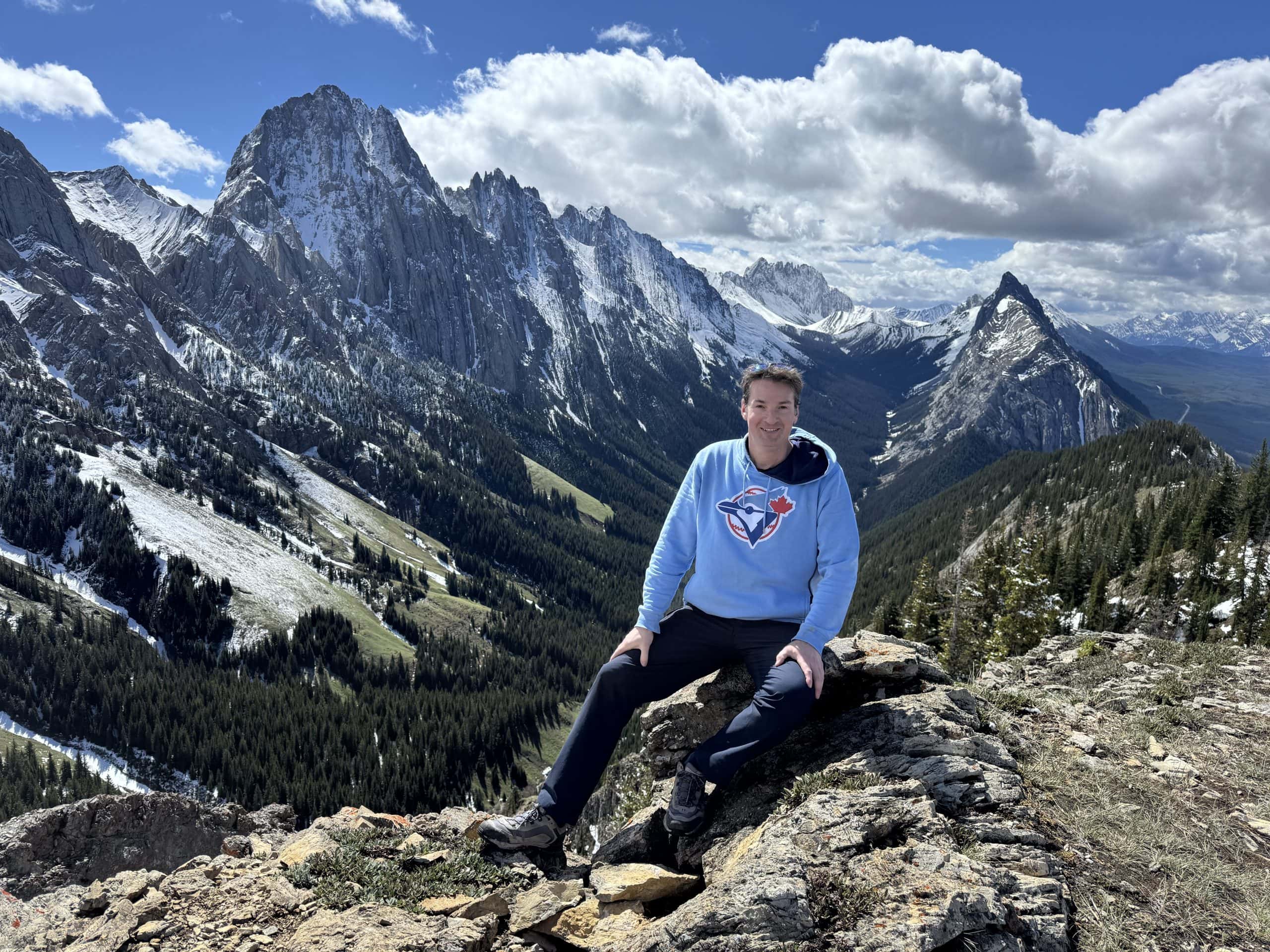 Ryan at the King Creek Ridge summit in Kananaskis overlooking Mount Lougheed, the Opal Range, and the surrounding Rocky Mountains.