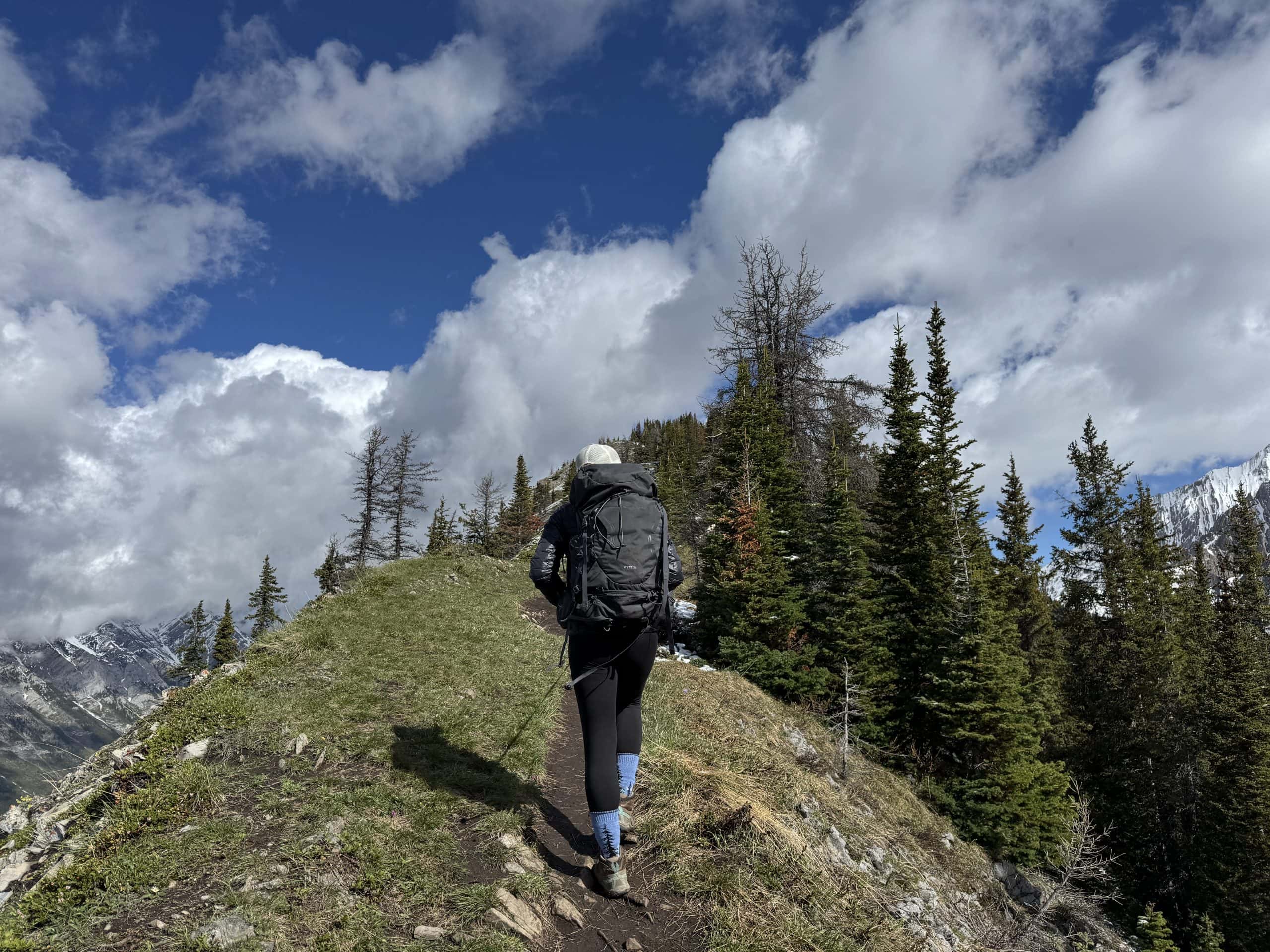 Hiker following the King Creek Ridge ridgeline trail with panoramic mountain views in Kananaskis Country.