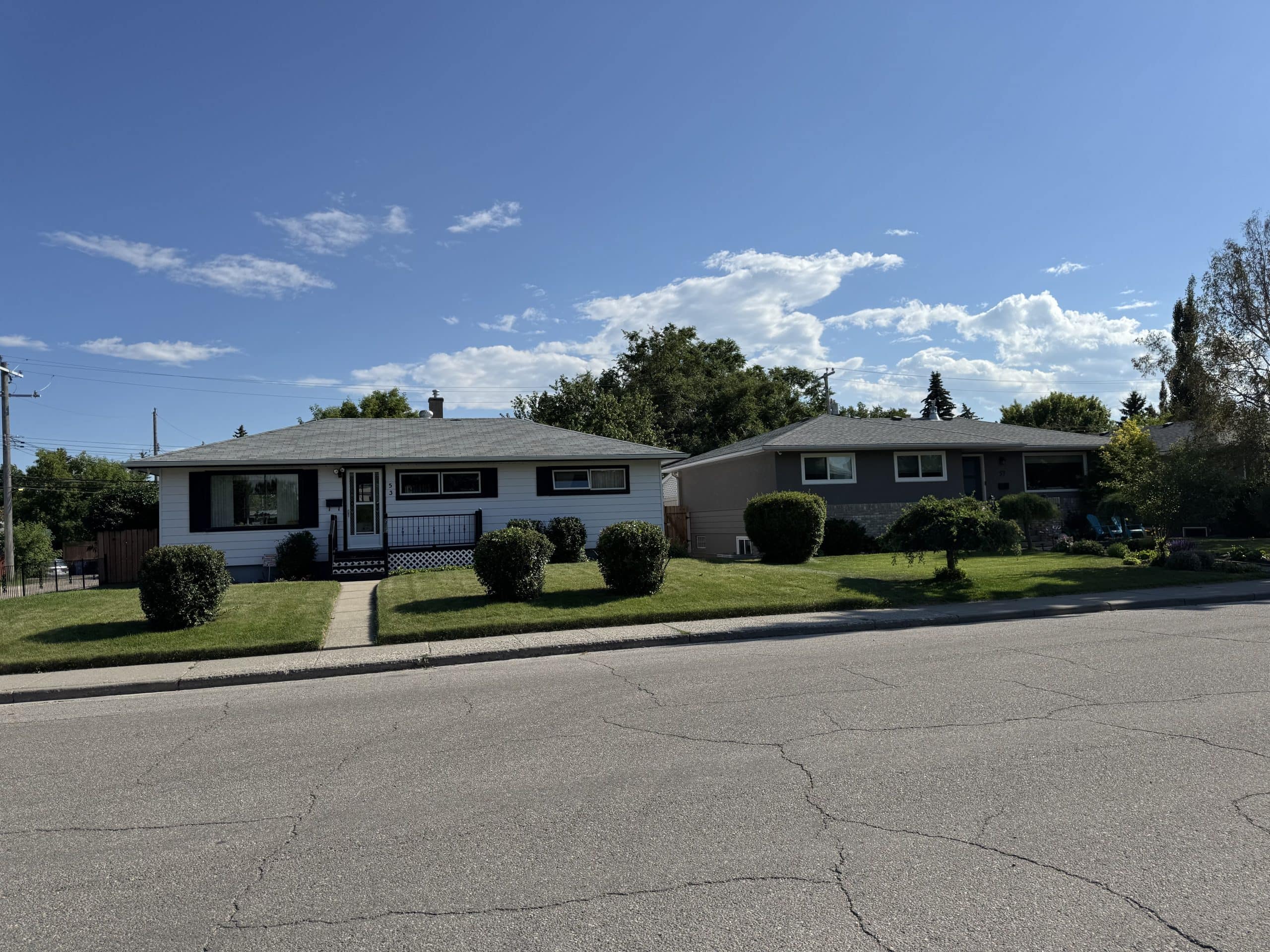 Wide view of well maintained mid century homes on a quiet residential street in West Calgary, showcasing the mature character and spacious lots found in established neighbourhoods.
