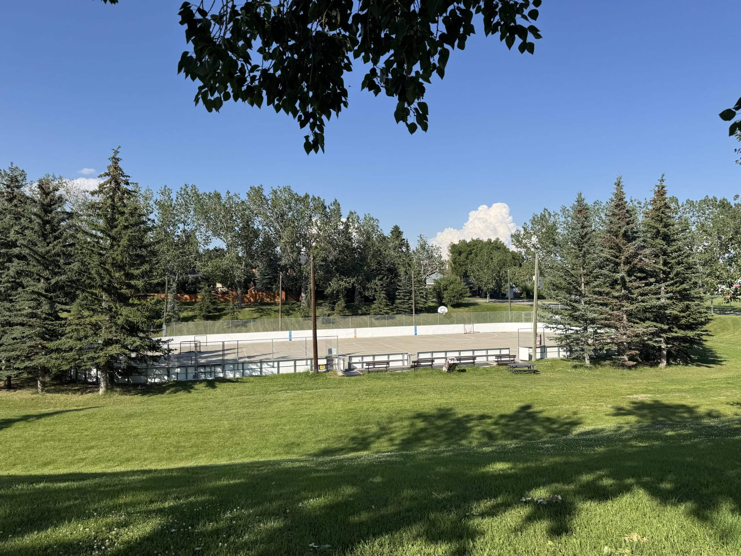 Outdoor skating rink and green space in Glendale, Calgary, surrounded by mature trees and parkland.