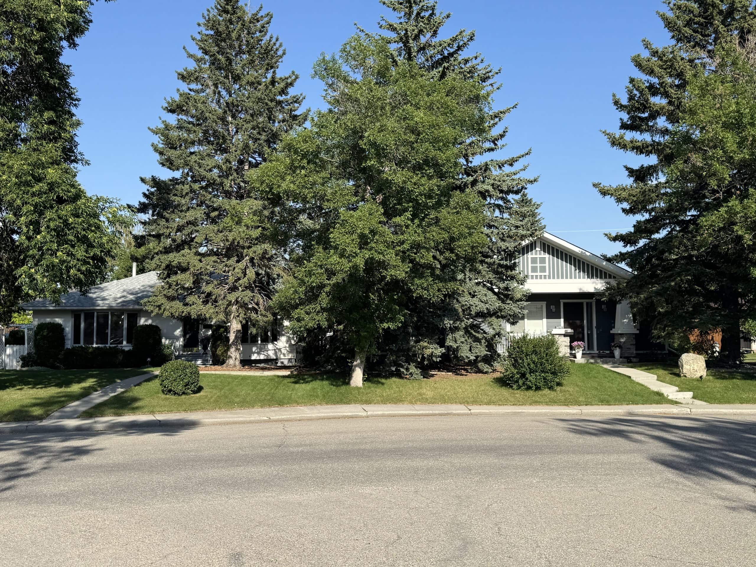 Detached single family homes with mature trees along a quiet residential street in Glendale, Calgary.