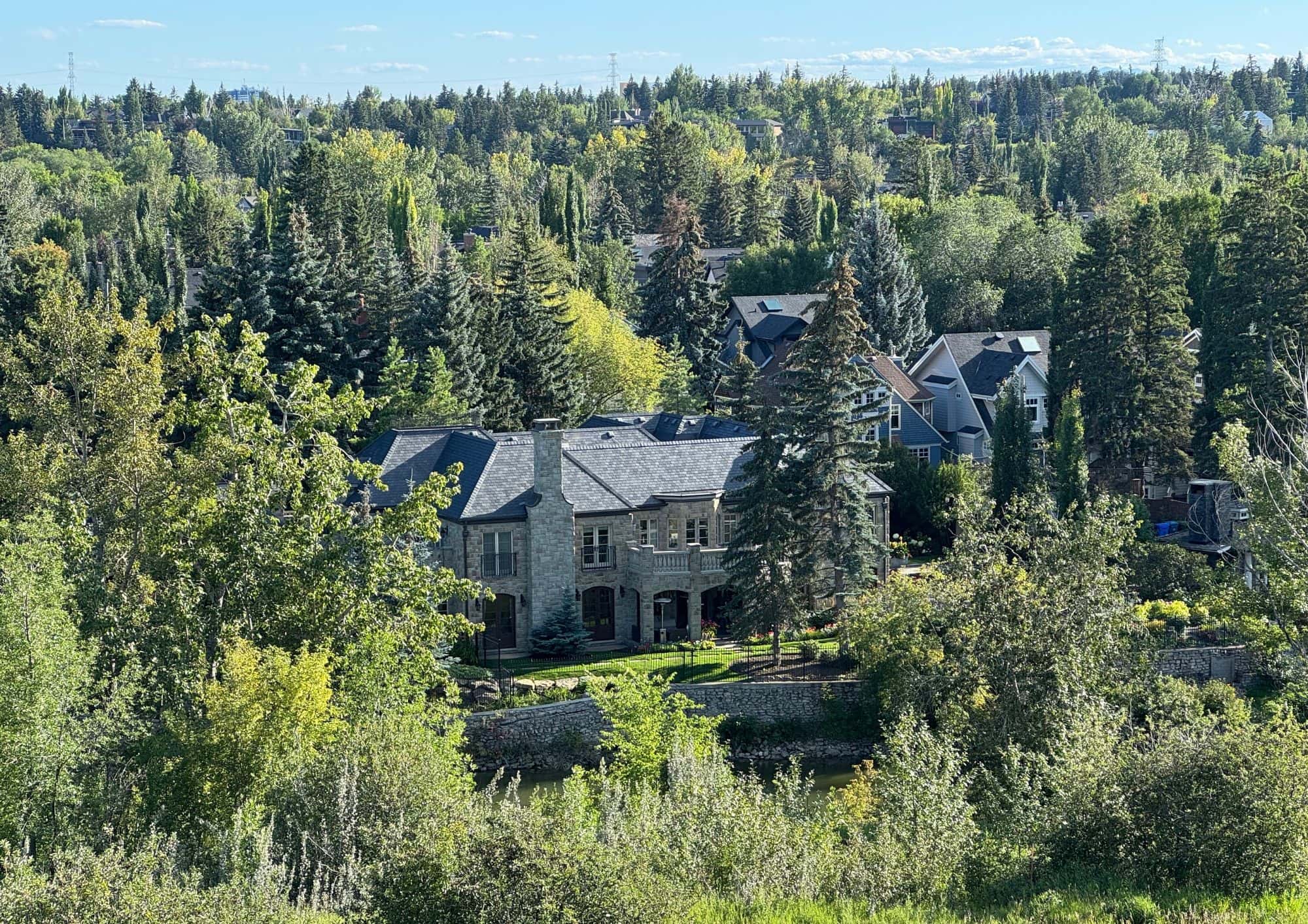 Luxury homes in Elbow Park, Calgary, viewed from the ridge overlooking mature trees, estate properties, and the Elbow River valley.
