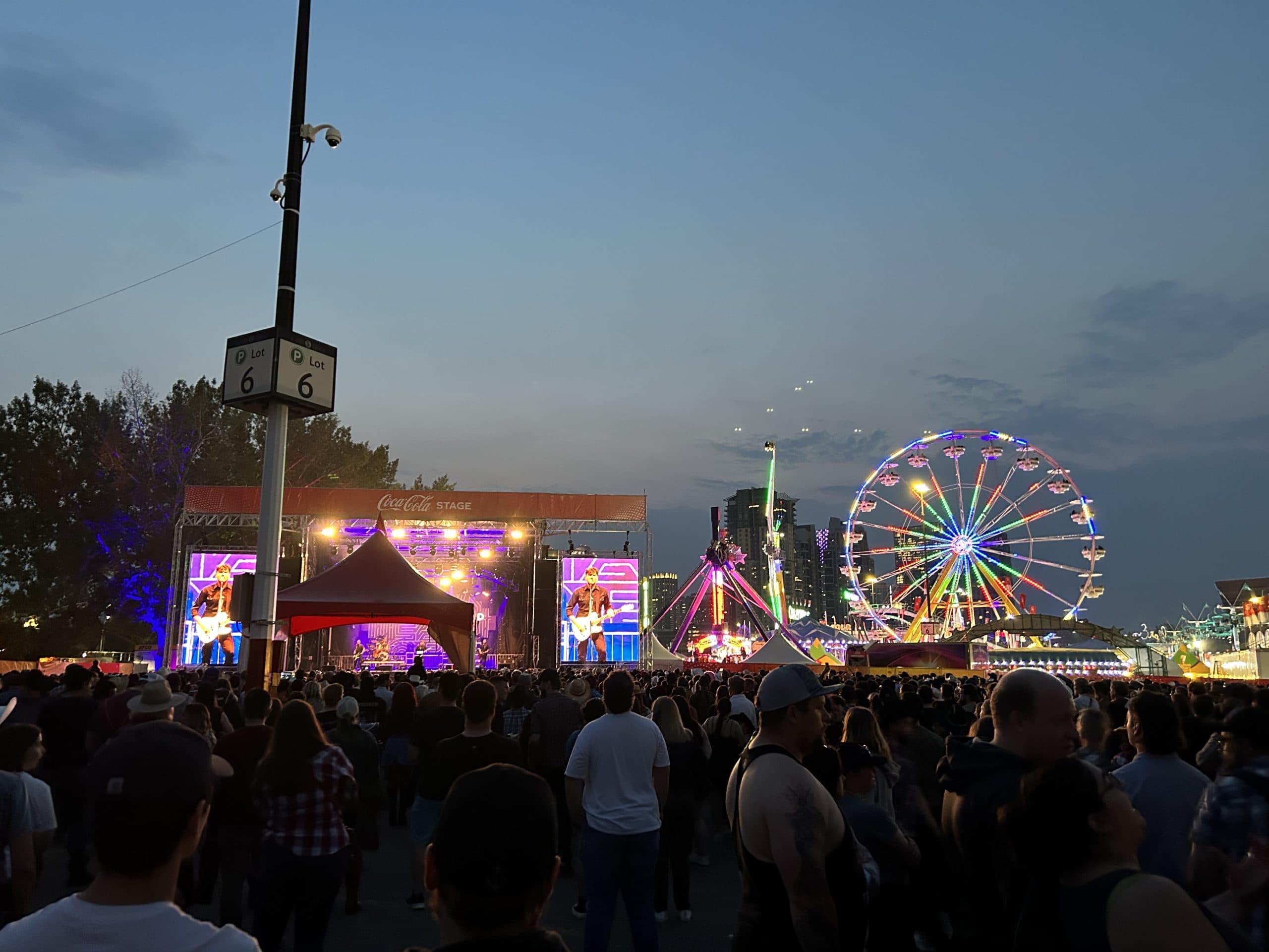 Crowd enjoying live music, midway rides and the Ferris wheel at the Calgary Stampede in Calgary, Alberta.