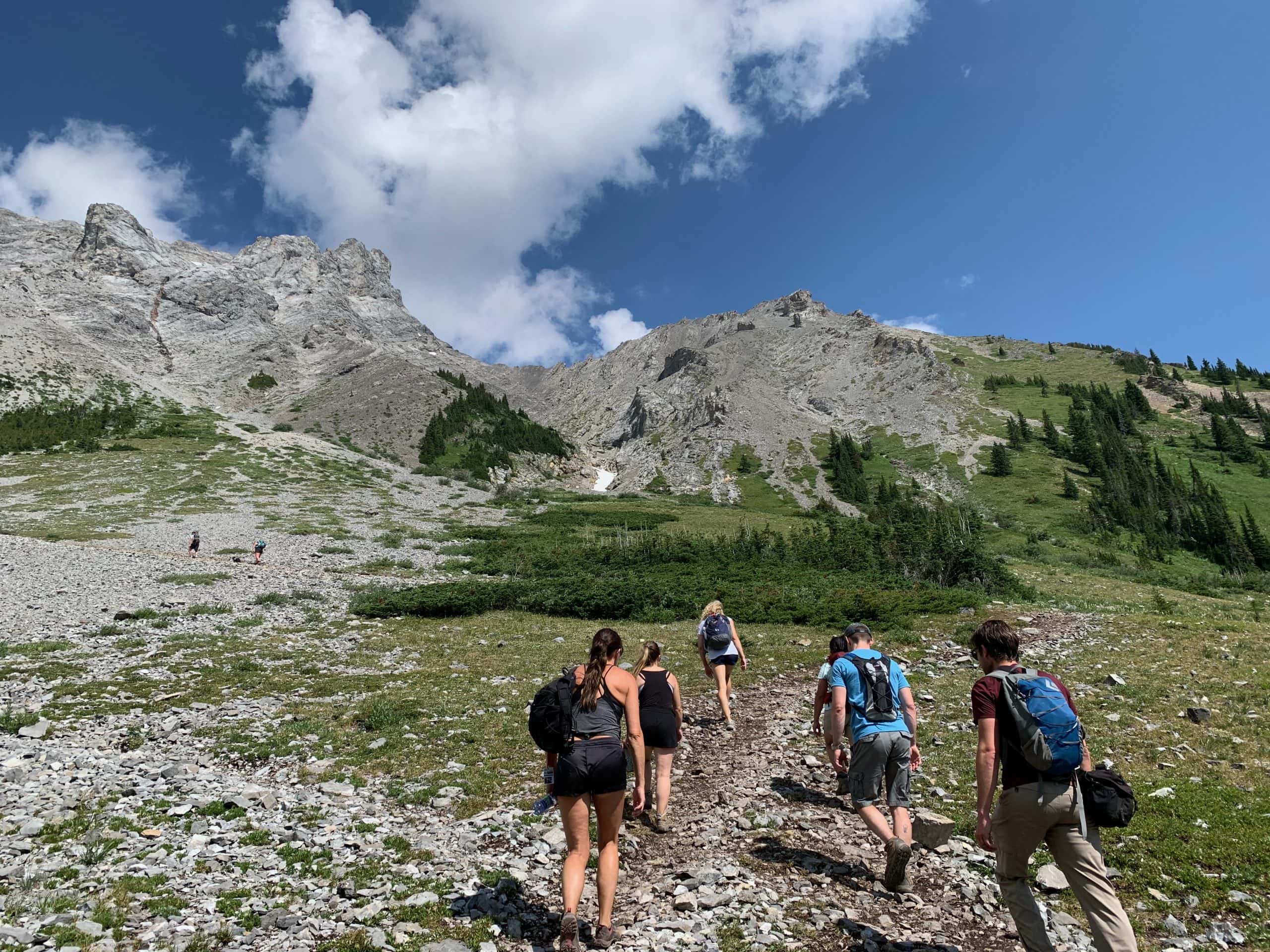 Hikers climbing a mountain trail in Kananaskis Country, Alberta, surrounded by the Canadian Rockies.

