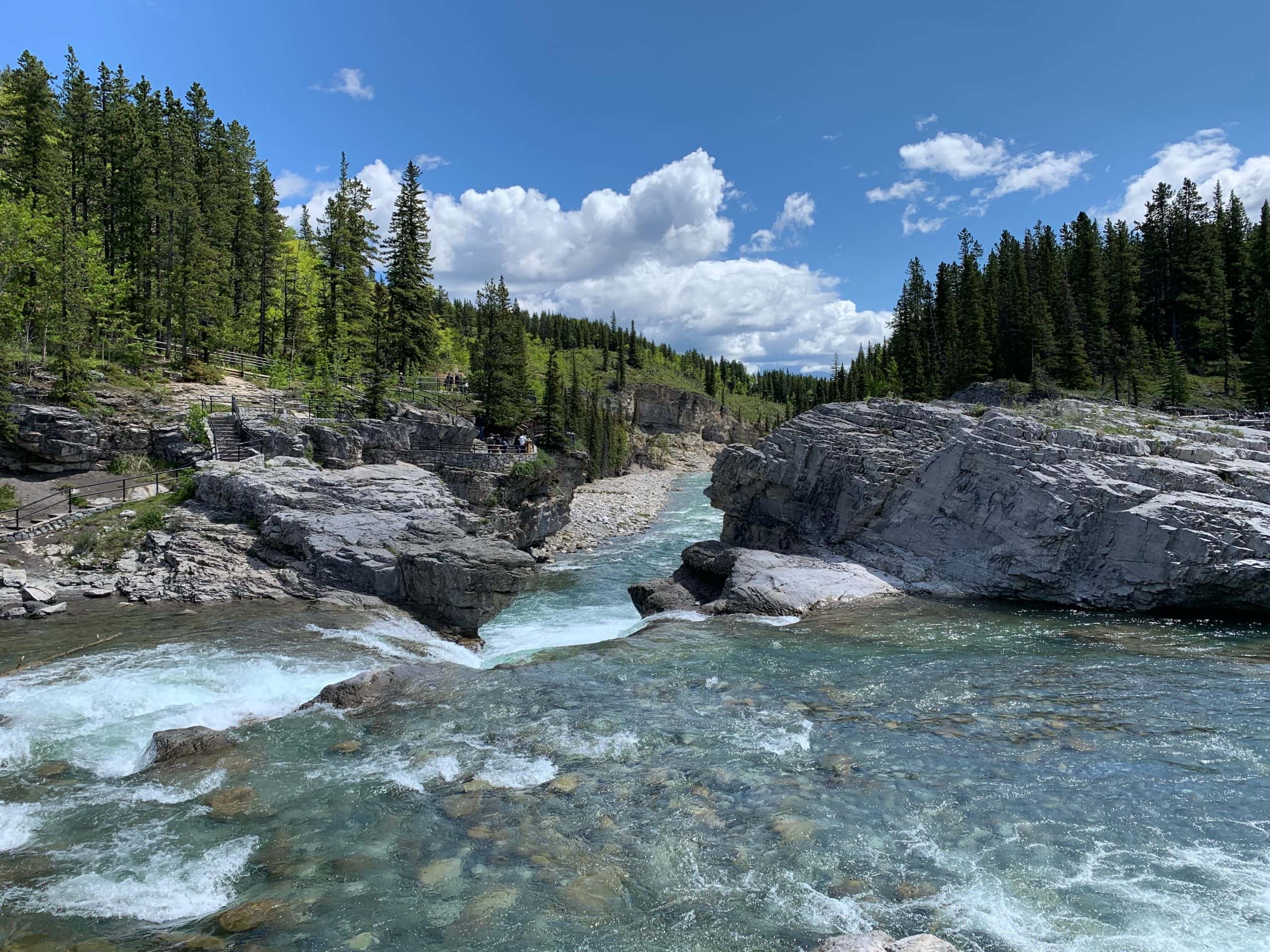 Elbow Falls near Bragg Creek, Alberta, with rushing turquoise water flowing through a rocky canyon surrounded by forest.