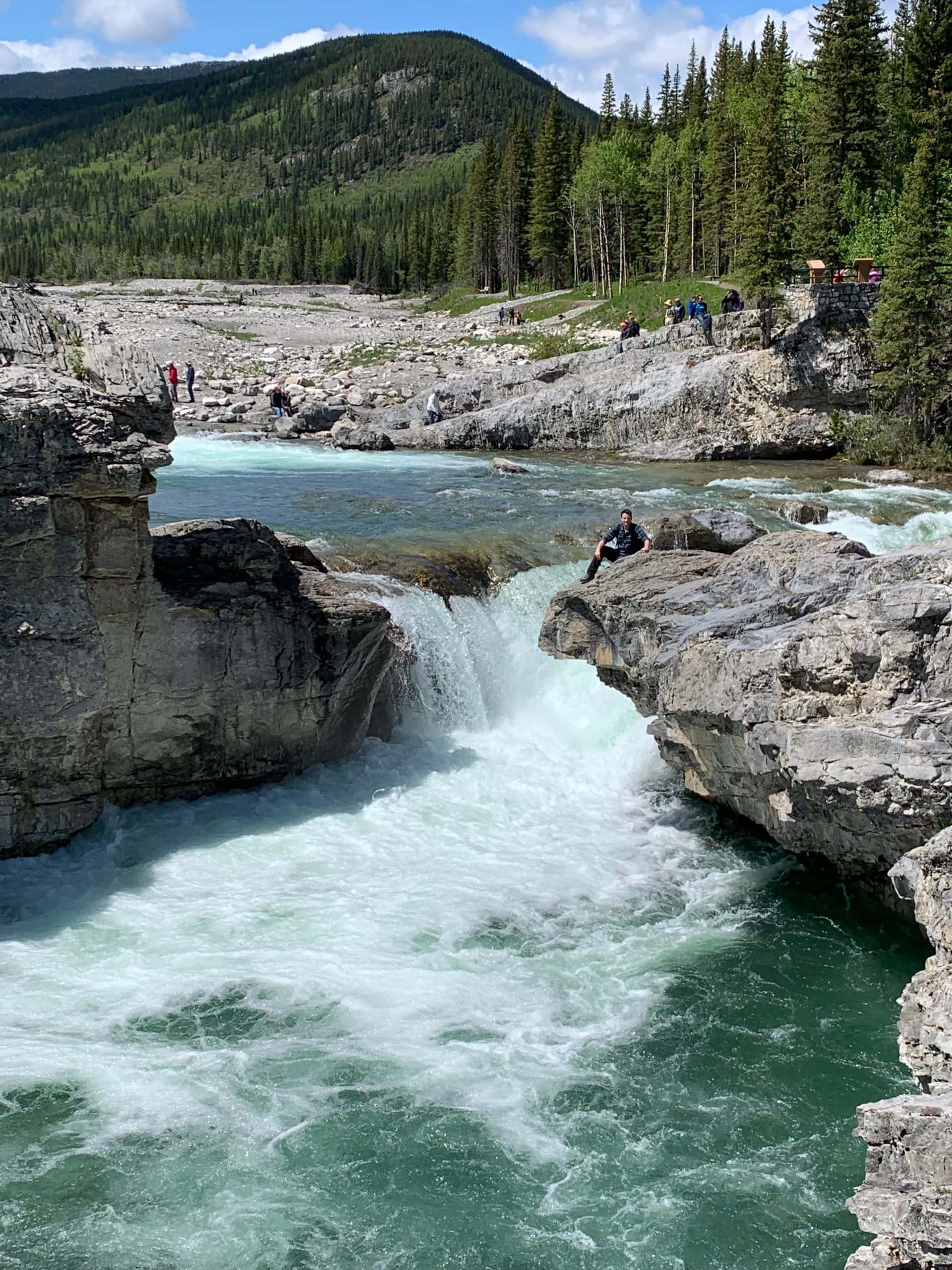 Elbow Falls near Bragg Creek, Alberta, with rushing water flowing through the rocky Elbow River valley during spring runoff.