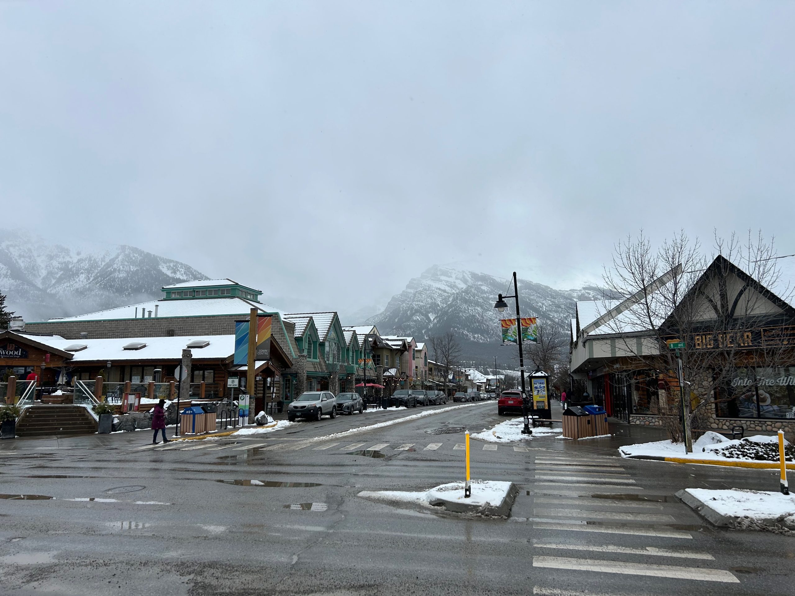 Downtown Canmore, Alberta, on a snowy winter day with local shops, restaurants and the Canadian Rockies in the background.