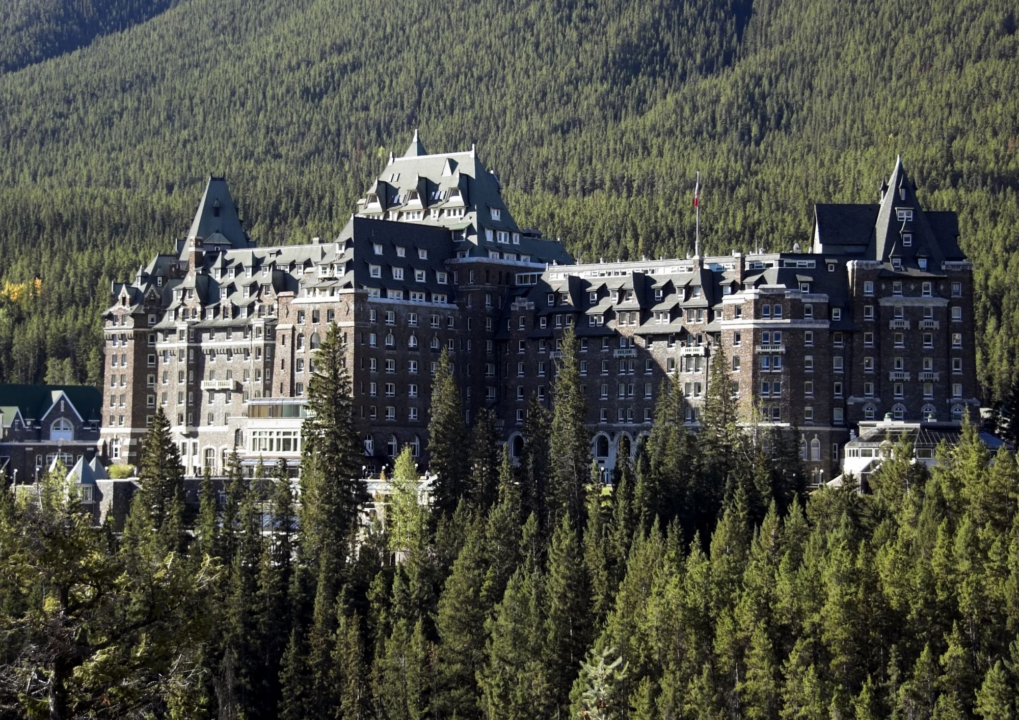 Fairmont Banff Springs hotel surrounded by forest and the Canadian Rockies in Banff National Park, Alberta.
