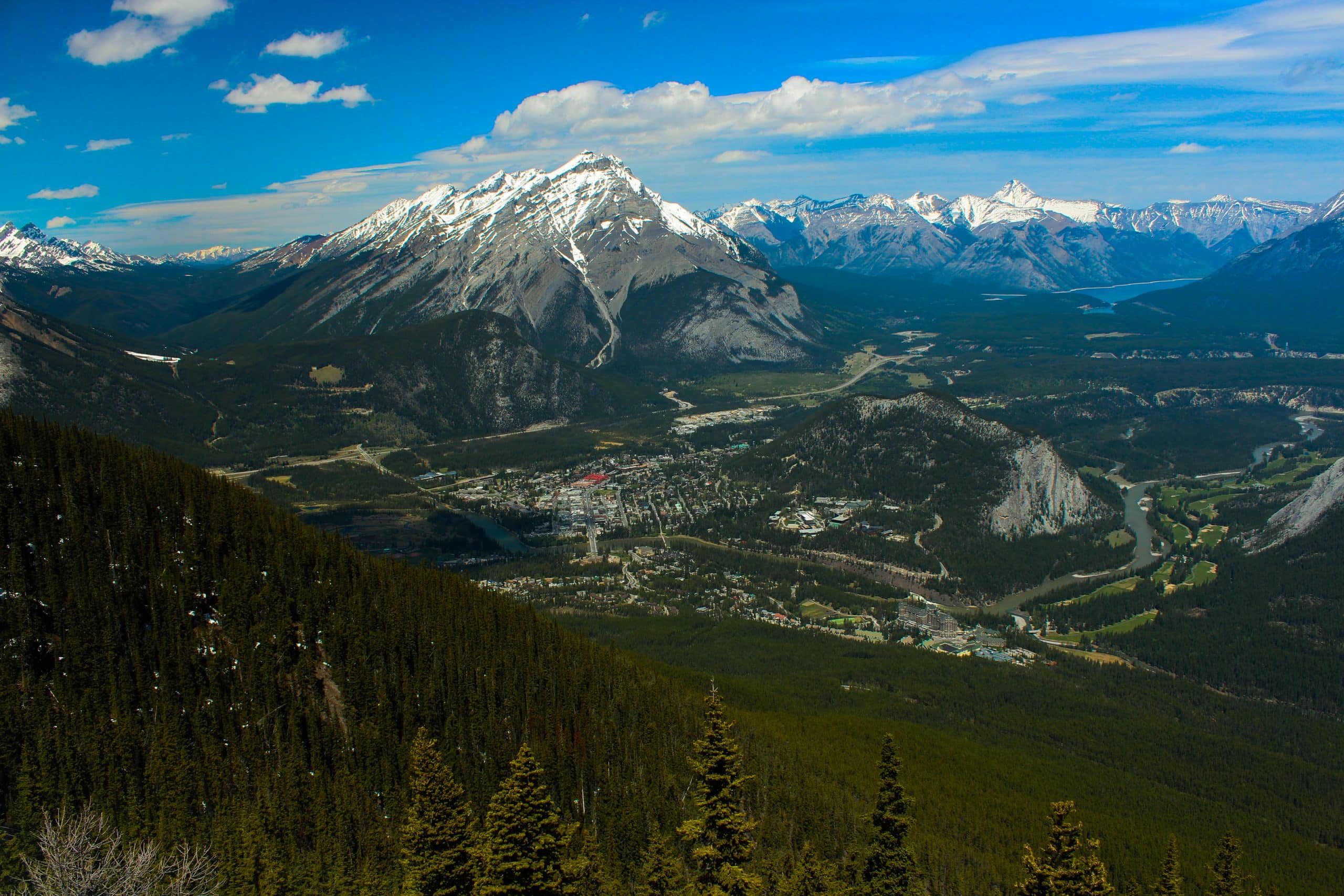 Aerial view over Banff, Alberta, with the Bow River, Banff townsite and snow capped Rocky Mountains stretching across Banff National Park.