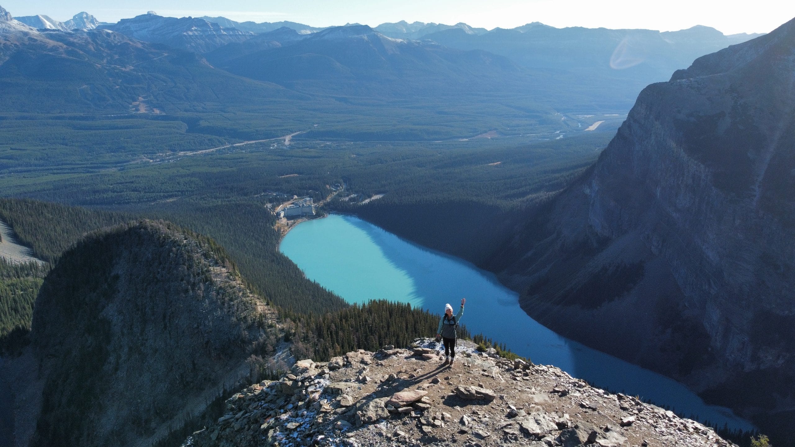 Hiker overlooking turquoise Lake Louise and the surrounding Rocky Mountains in Banff National Park, Alberta.